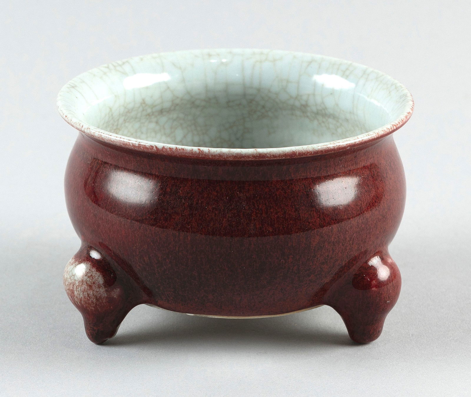 CHINESE OXBLOOD RED GLAZE PORCELAIN CENSER Early 19th Century Height 3.25". Diameter 5".: CHINESE OXBLOOD RED GLAZE PORCELAIN CENSEREarly 19th CenturySquat ovoid form with three stump feet. Crackleware interior glaze. Labels on base for Australian Antique Dealers Association and the CP Lee