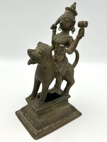 INDIAN BRASS FIGURE OF A MULTI-ARMED DEITY RIDING A LION 19th Century Height 6.5".