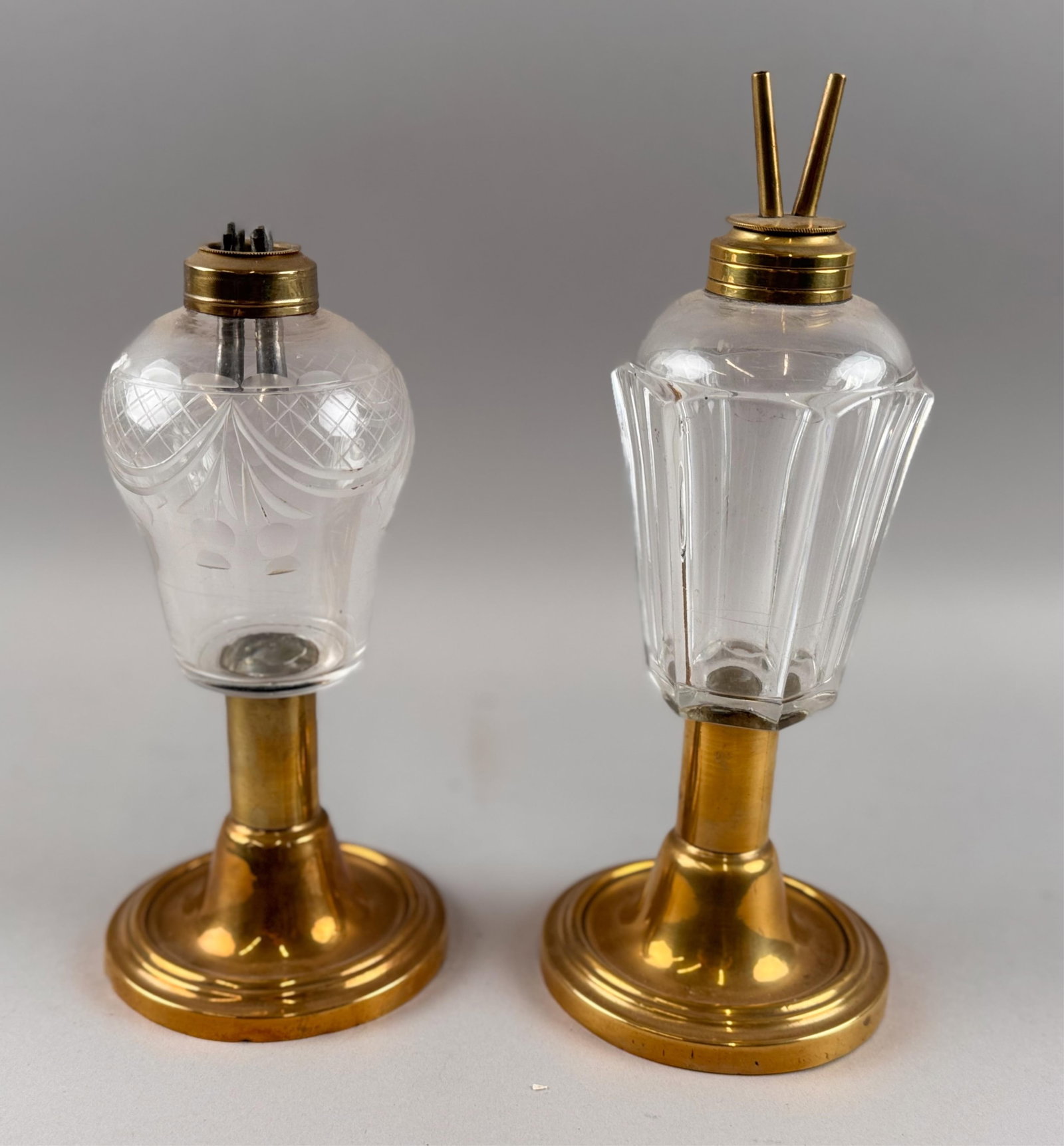 TWO CLEAR GLASS AND BRASS WHALE OIL LAMPS 19th Century Heights 8.5" and 10.5".: TWO CLEAR GLASS AND BRASS WHALE OIL LAMPS 19th Century One with fan and swag cutting. Heights 8.5" and 10.5".