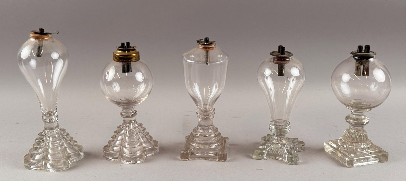 FIVE CLEAR GLASS WHALE OIL LAMPS 19th Century Heights from 6.75" to 7".: FIVE CLEAR GLASS WHALE OIL LAMPS 19th Century All with freeblown fonts and pressed bases. Heights from 6.75" to 7".
