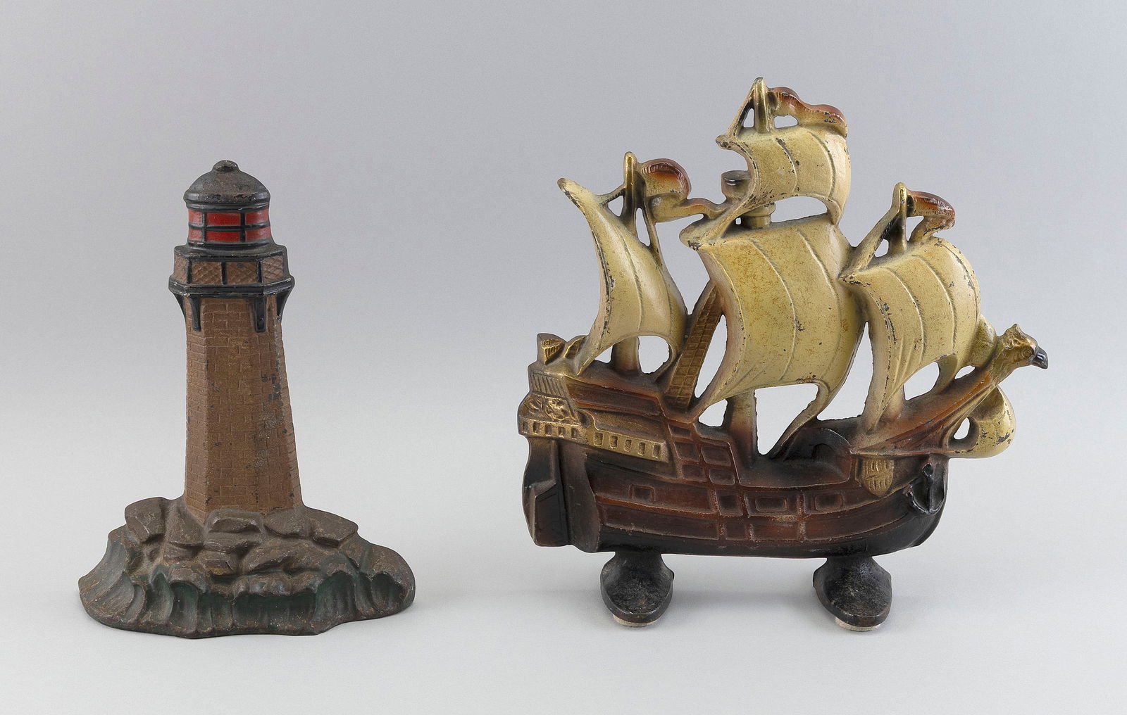 TWO CAST IRON NAUTICAL MOTIF DOORSTOPS 20th Century Heights 10" and 12".: TWO CAST IRON NAUTICAL MOTIF DOORSTOPS20th CenturyA galleon and a lighthouse with rock and wave base.Heights 10" and 12".