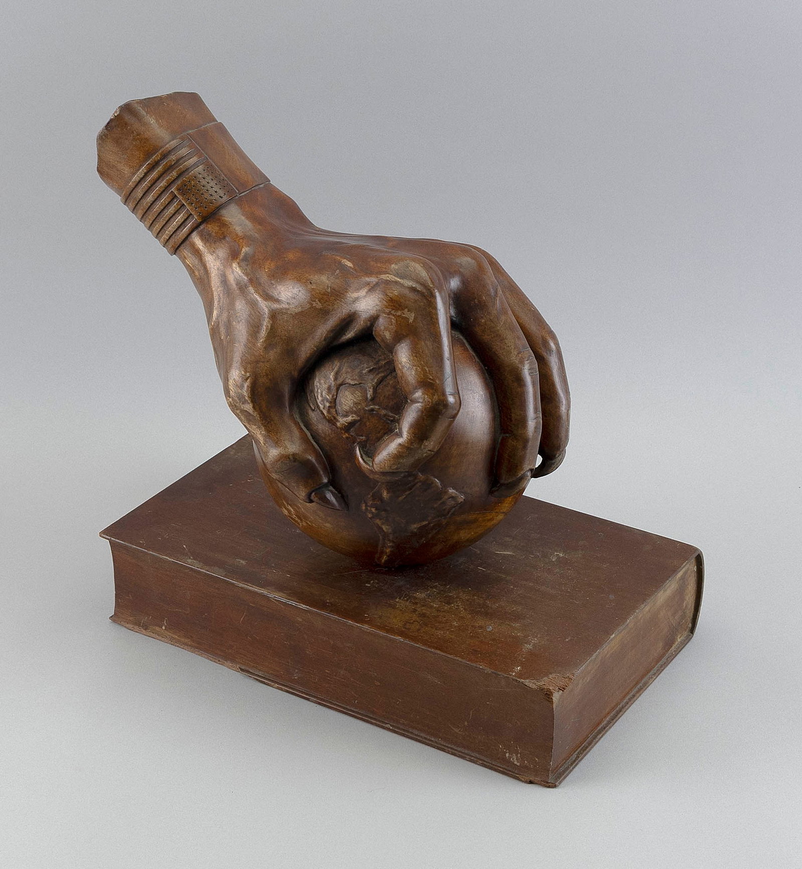 POLITICALLY-THEMED MAHOGANY CARVING Post-World War I Height 14". Length 13". Width 8".: POLITICALLY-THEMED MAHOGANY CARVING Post-World War I Formed as a hand with a U.S. 48-star flag cuff grasping a globe atop a book. Unsigned. Height 14". Length 13". Width 8".