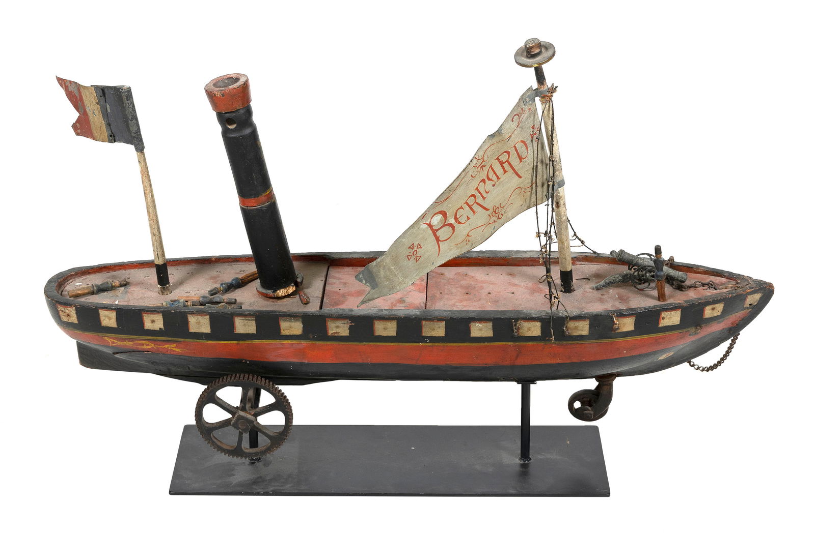 FRENCH FOLK ART SHIP PULL TOY 19th Century Height 32". Length 47". Width 10".: FRENCH FOLK ART SHIP PULL TOY19th CenturyModeled after the Mont Saint-Bernard. Black, white and red painted ship flies a tin red and white "Bernard" flag and a French flag. Iron wheels. Includes nine
