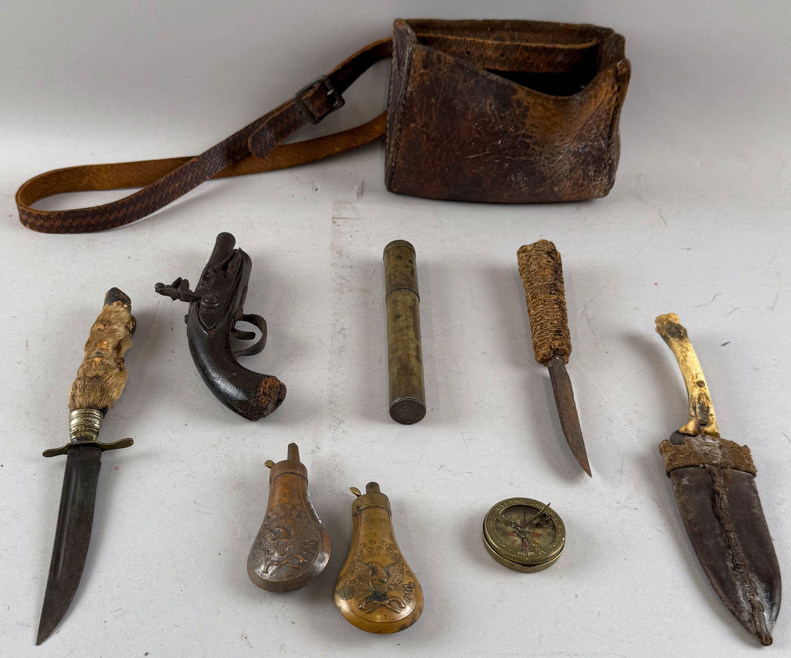 LEATHER POUCH AND ASSORTED HUNTING ITEMS 19th Century: LEATHER POUCH AND ASSORTED HUNTING ITEMS19th CenturyPouch with punched and lattice pattern decoration. Other items include a copper eagle gun powder flask, a pistol, a corncob-handled knife, an animal