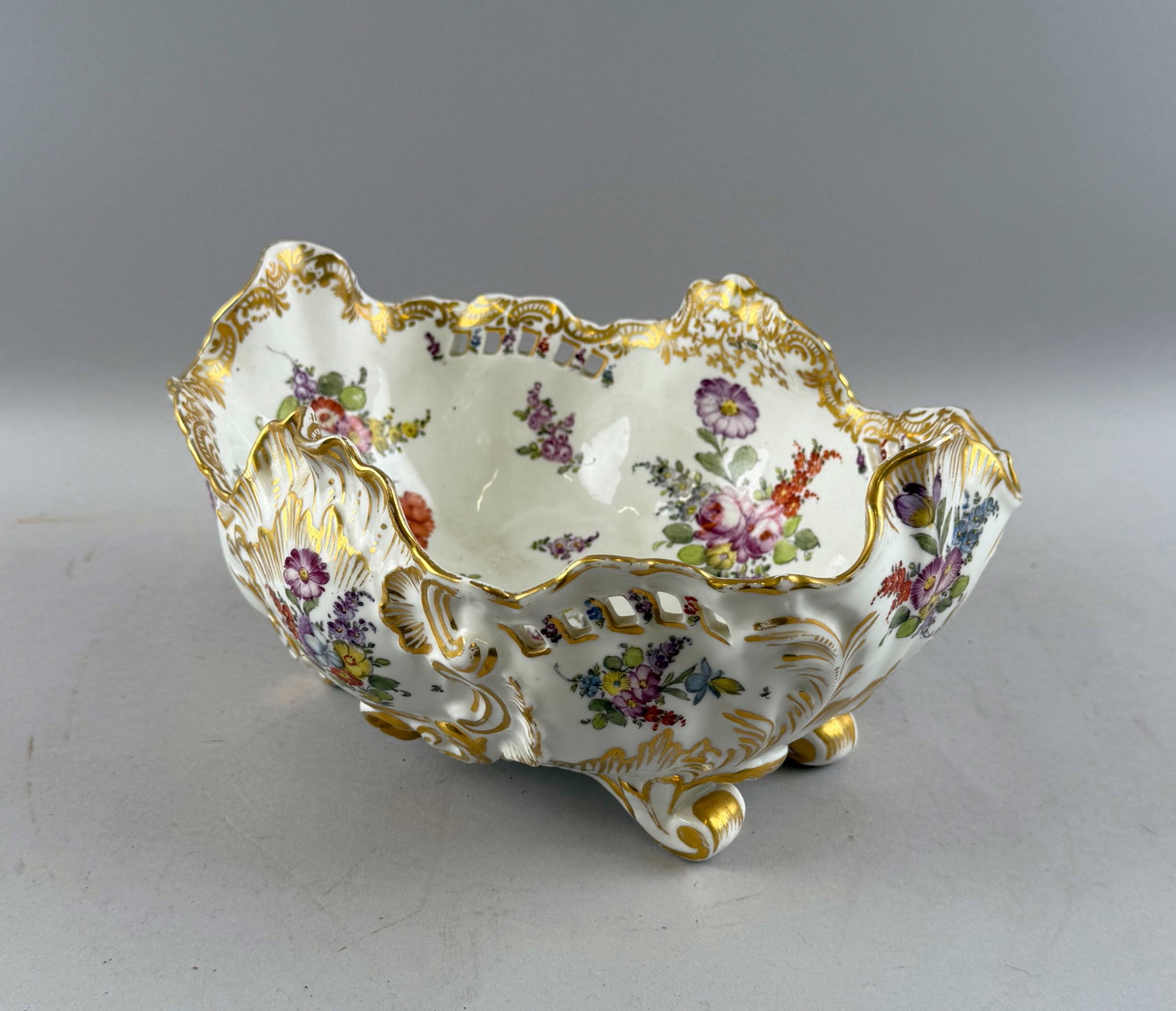 DRESDEN-STYLE PORCELAIN CENTERPIECE BOWL Late 19th Century Height 5.5". Length 10.25".: DRESDEN-STYLE PORCELAIN CENTERPIECE BOWL Late 19th Century Both interior and exterior with Famille Rose floral sprays and gilt highlights. Boldly shaped and pierced Rococo rim. Four scrolled feet. Blu