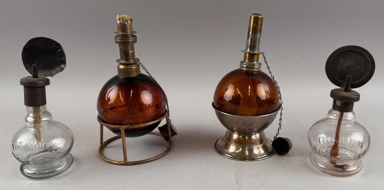 TWO PAIRS OF FLUID LAMPS 19th Century Heights 6" and 7".: TWO PAIRS OF FLUID LAMPS 19th Century A pair of "The Handy Night Lamp" and a pair of amber ball lamps on stands. Heights 6" and 7". Provenance: William Dixon Collection.