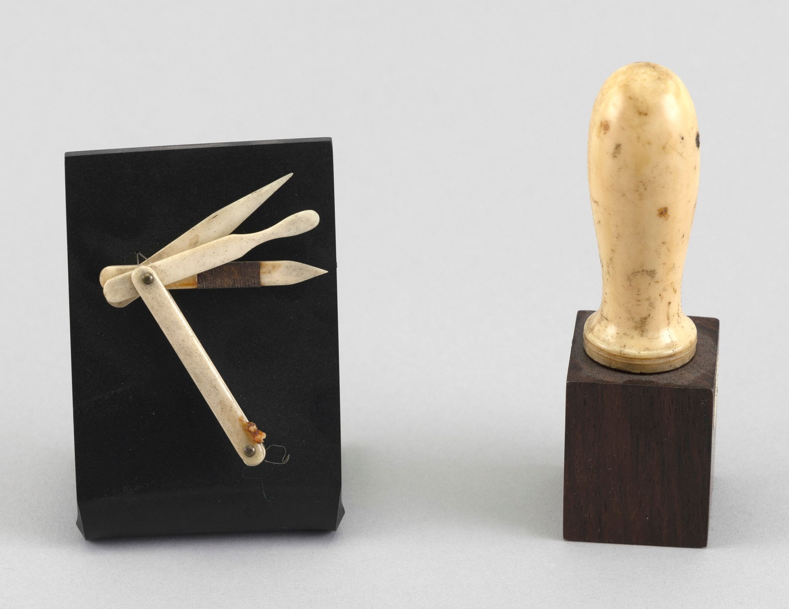 WHALEBONE SEWING KNIFE AND A WHALE IVORY ROLLING PIN HANDLE 19th Century Height on stands 4" and 5".: WHALEBONE SEWING KNIFE AND A WHALE IVORY ROLLING PIN HANDLE19th CenturyBoth displayed on wooden stands.Height on stands 4" and 5". Provenance:Barbara Johnson Collection; retains tags.