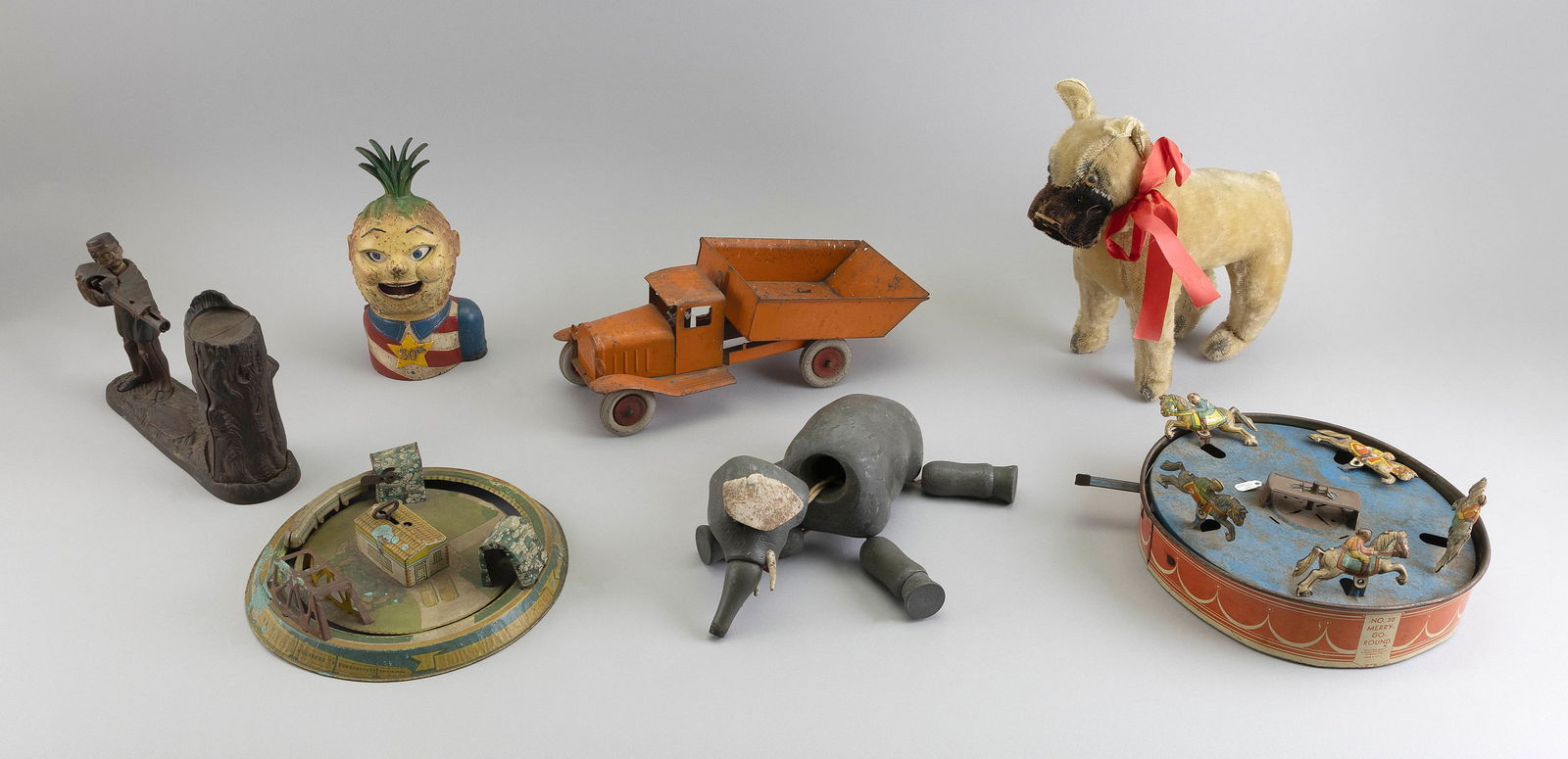 SEVEN TOYS 19th/20th Century Truck length 12".: SEVEN TOYS19th/20th CenturyTwo cast iron banks, a Steiff dog, a wooden elephant, a tin truck and two tin racing games.Truck length 12". Provenance:An Upstate New York Collection.