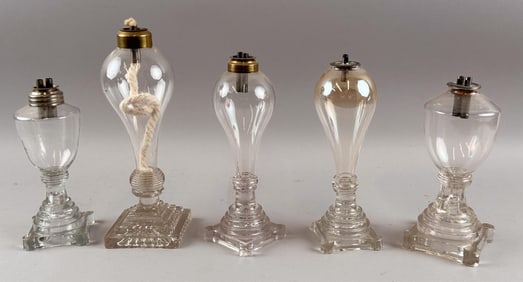 FIVE CLEAR GLASS WHALE OIL LAMPS First Quarter of the 19th Century Heights from 7.5" to 9.75".
