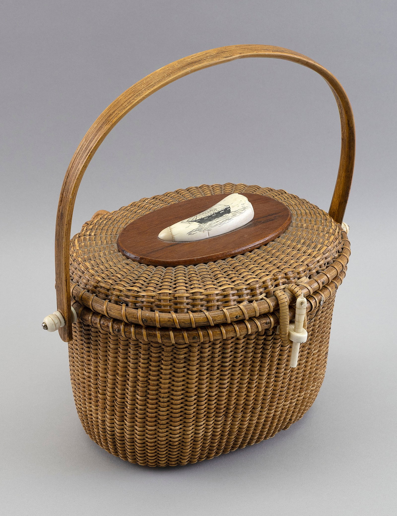 NANTUCKET BASKET PURSE ATTRIBUTED TO G.L. BROWN Nantucket, Massachusetts, 20th Century Height 7".: Y Y NANTUCKET BASKET PURSE ATTRIBUTED TO G.L. BROWN Nantucket, Massachusetts, 20th Century Hinged lid mounted with an engraved whale's tooth depicting a three-masted vessel. Retains G.L. Brown card. H