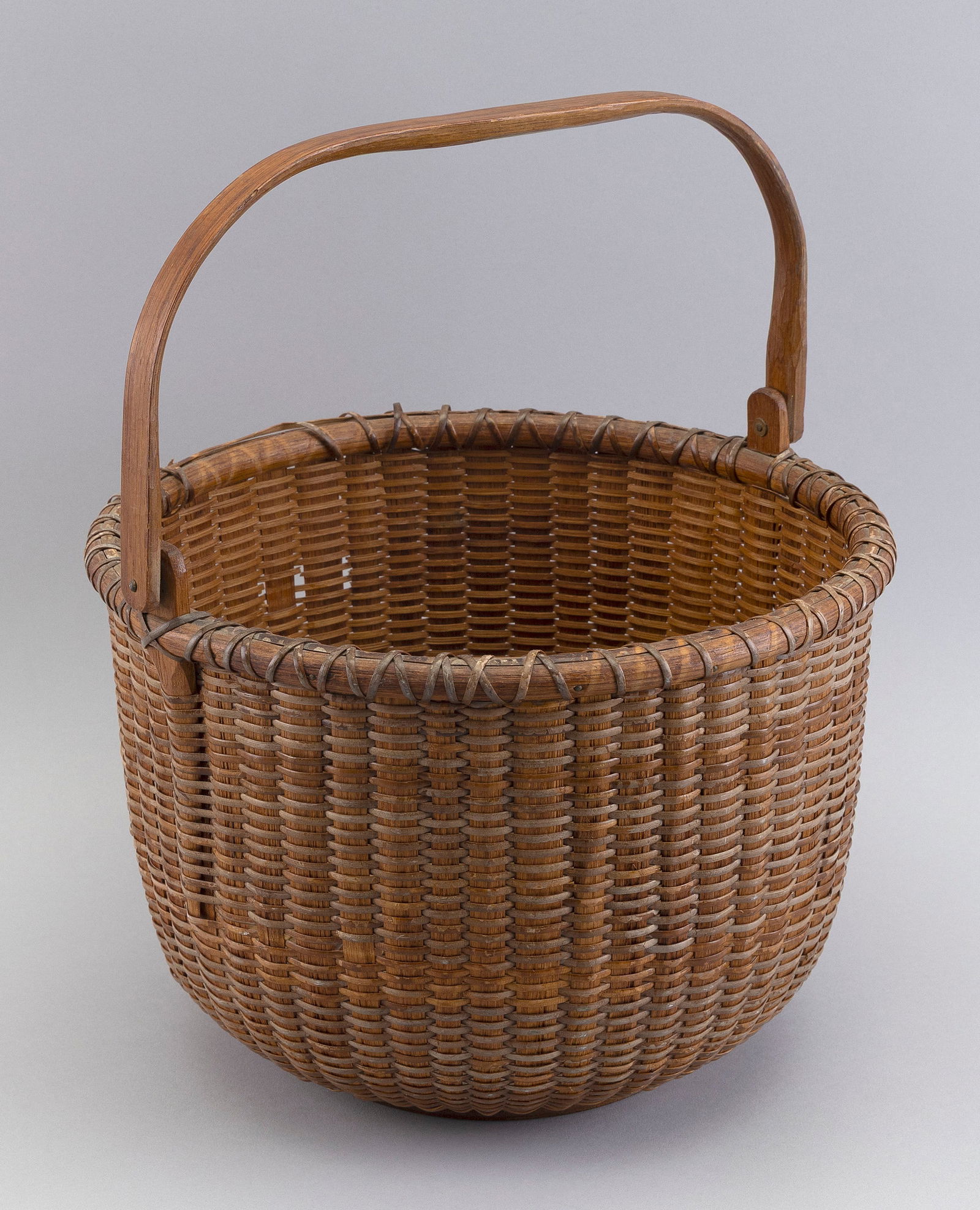 JOSE FORMOSO REYES NANTUCKET BASKET Nantucket, Massachusetts, 1902-1980 Height 8". Diameter 12".: JOSE FORMOSO REYES NANTUCKET BASKETNantucket, Massachusetts, 1902-1980With swing handle. Signed on underside "Made in Nantucket by Jose Formoso Reyes".Height 8". Diameter 12".