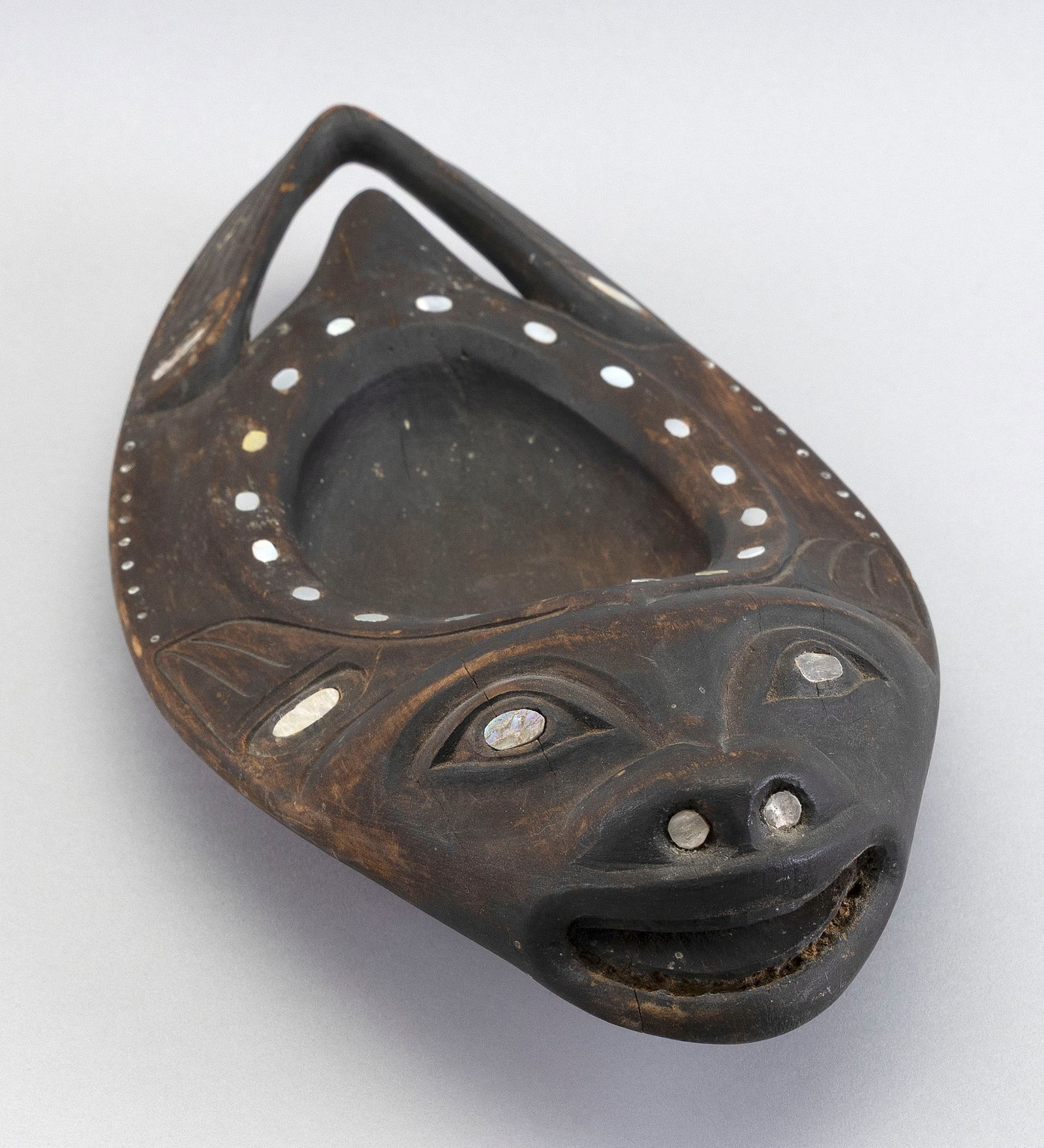 RARE INUIT INLAID WOODEN GREASE BOWL Late 19th Century Length 15".: RARE INUIT INLAID WOODEN GREASE BOWLLate 19th CenturyAttributed to Rudolph Walton and Augustus Bean. Formed as a seal, its features defined by abalone and bead inlay. Stained dark brown. Bears a parti