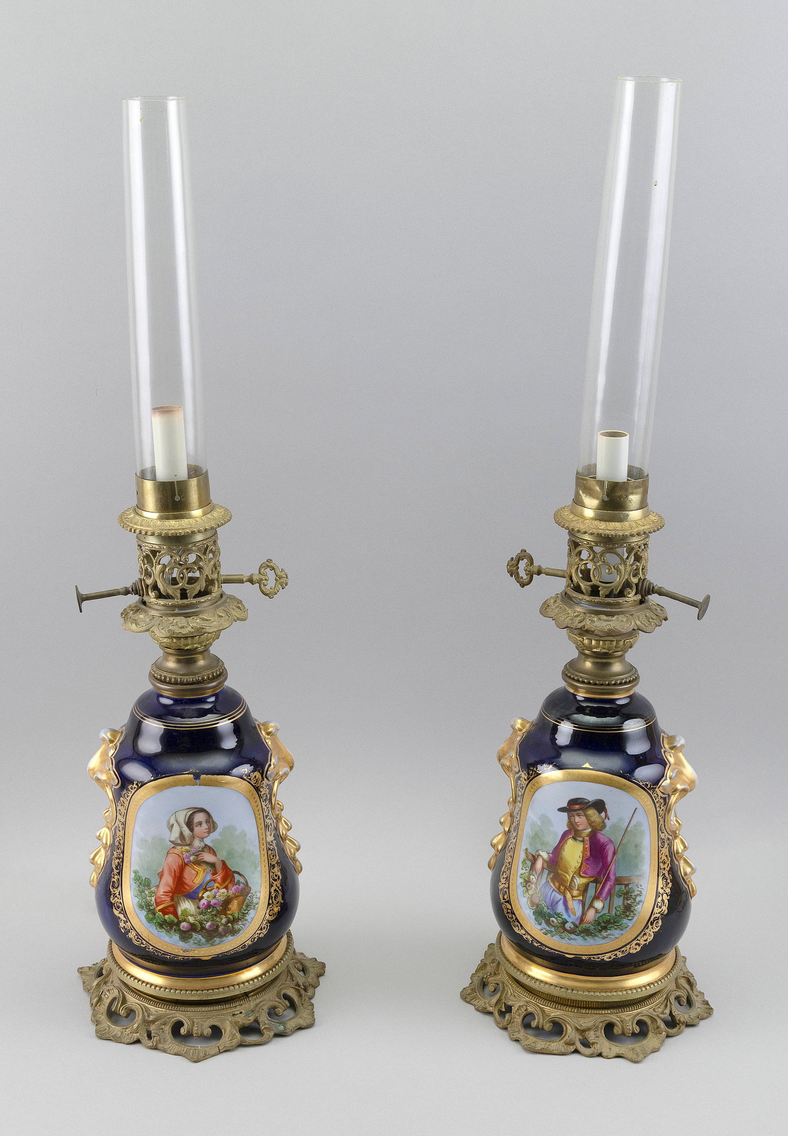 PAIR OF PARIS PORCELAIN TABLE LAMPS France, 19th Century Total heights 22". Shade diameters 6.5".: PAIR OF PARIS PORCELAIN TABLE LAMPSFrance, 19th CenturyHand-painted portrait and floral medallions against a cobalt blue ground with gilt embellishments. Painted white metal bases and lamp fittings. C