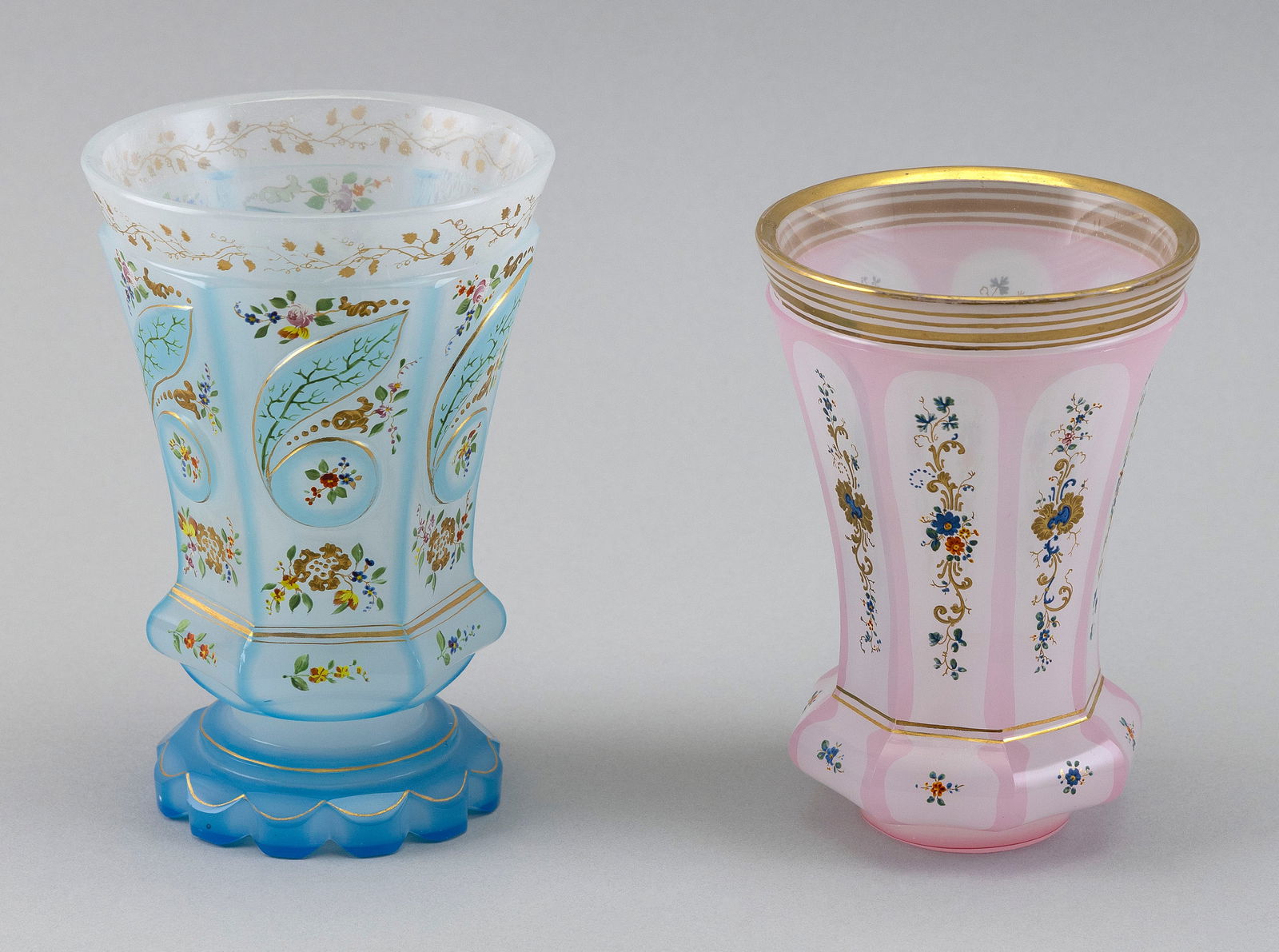 TWO RARE BOHEMIAN BIEDERMEIER OVERLAY GLASS BEAKERS 19th Century Heights 5" and 5.5".: TWO RARE BOHEMIAN BIEDERMEIER OVERLAY GLASS BEAKERS19th CenturyOne pink to opaque white and one blue to opaque white, both with enameled floral decoration and gilt embellishments.Heights 5" and 5.5".