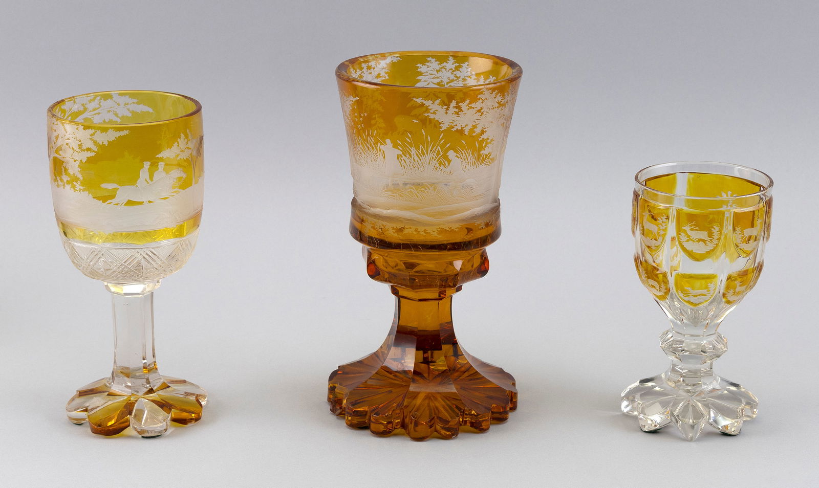 THREE BOHEMIAN BIEDERMEIER AMBER FLASHED AND ENGRAVED CHALICES Mid-19th Century Heights 6.25", 8.5": THREE BOHEMIAN BIEDERMEIER AMBER FLASHED AND ENGRAVED CHALICESMid-19th CenturyAll with hunting and stag decoration.Heights 6.25", 8.5" and 9.25". Provenance:The Estate of Harold Smalley, Osterville