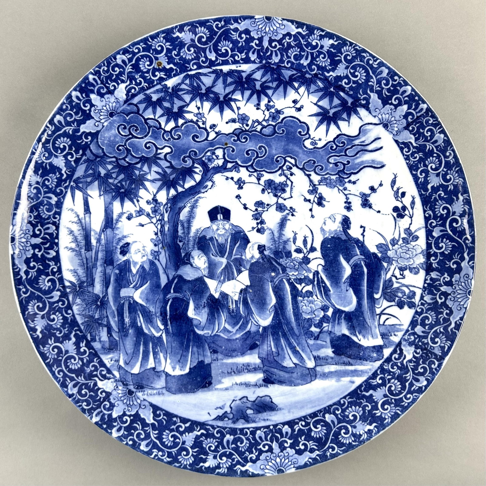 JAPANESE BLUE AND WHITE PORCELAIN CHARGER 20th Century Diameter 18".: JAPANESE BLUE AND WHITE PORCELAIN CHARGER 20th Century Decoration of five sages in a garden landscape. Paulownia flower and vine border. Diameter 18".