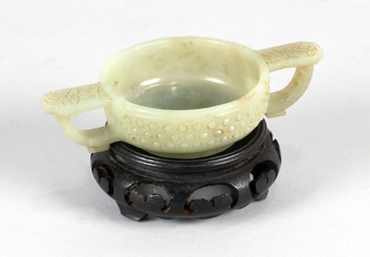 CHINESE ARCHAIC JADE TWO-HANDLED CUP Height 1". Width across handles 5". With wood stand.