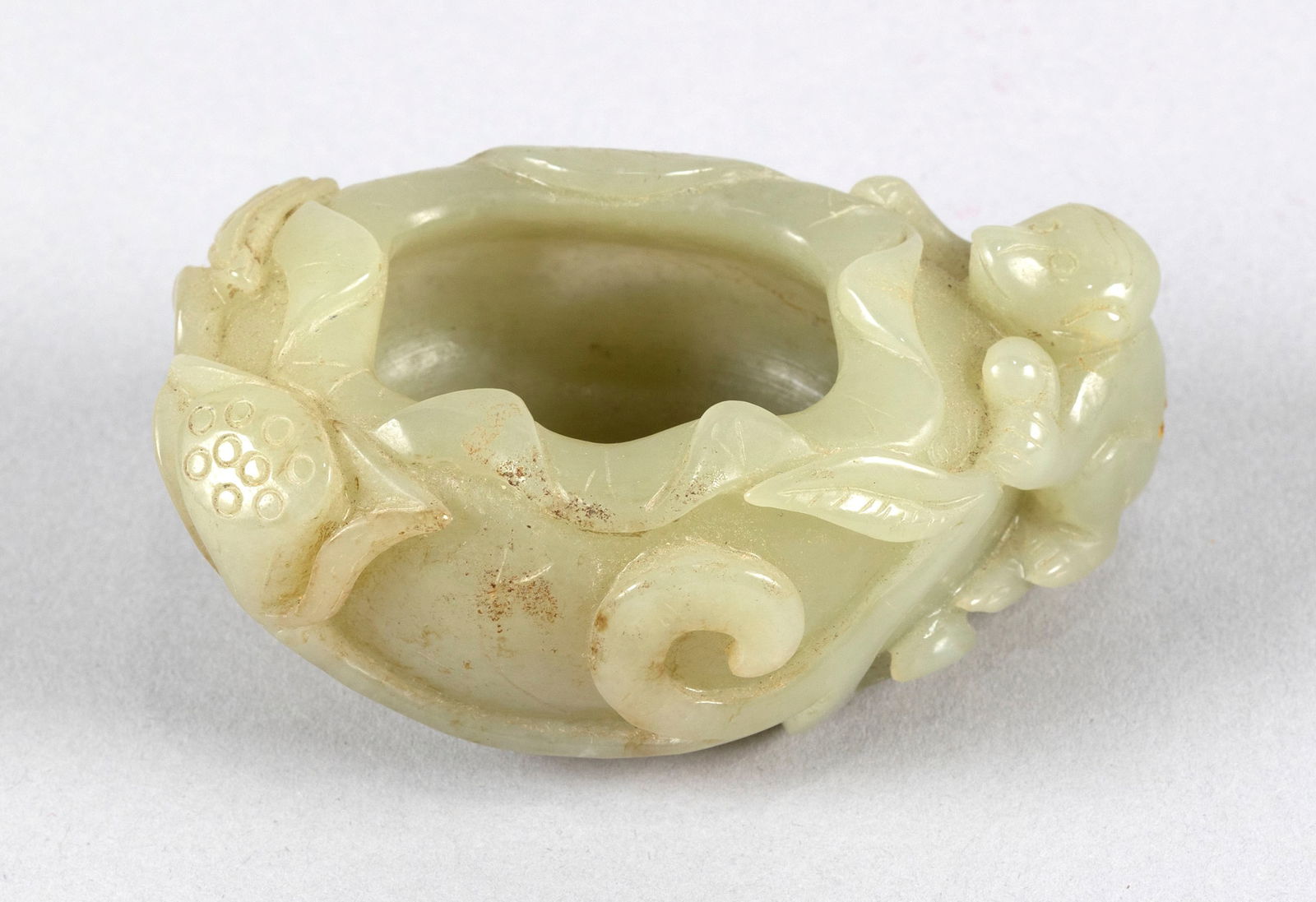 CHINESE LIGHT CELADON JADE WATER DROPPER Late 19th/Early 20th Century Height 2". Length 3".: CHINESE LIGHT CELADON JADE WATER DROPPERLate 19th/Early 20th CenturyIn the form of a monkey climbing the side of a furled lotus leaf with pods.Height 2". Length 3".