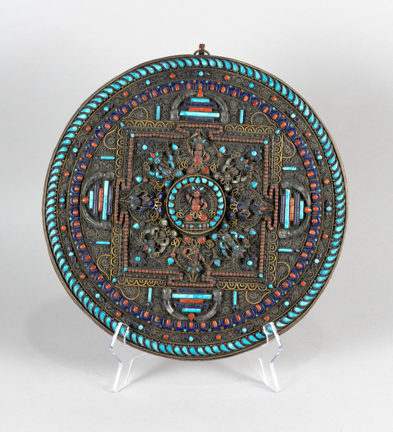TIBETAN DECORATIVE MANDALA Late 19th Century Diameter 14".: TIBETAN DECORATIVE MANDALA Late 19th Century Inset lapis, coral and turquoise cabochons amidst filigree figural and floral decoration. Marked verso. Diameter 14".