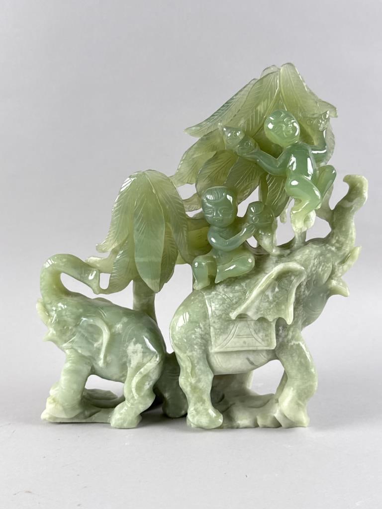 JADE FIGURE GROUP 19th Century Height 11.25". Width 10". Depth 3".: JADE FIGURE GROUP19th CenturyTwo men picking fruit off a tree while riding on the back of an elephant being tailed by its young.Height 11.25". Width 10". Depth 3".