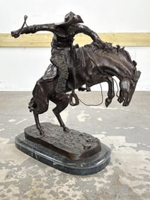 AFTER FREDERICK REMINGTON (20th Century,), "The Bronco Buster"., Bronze on a green marble base,