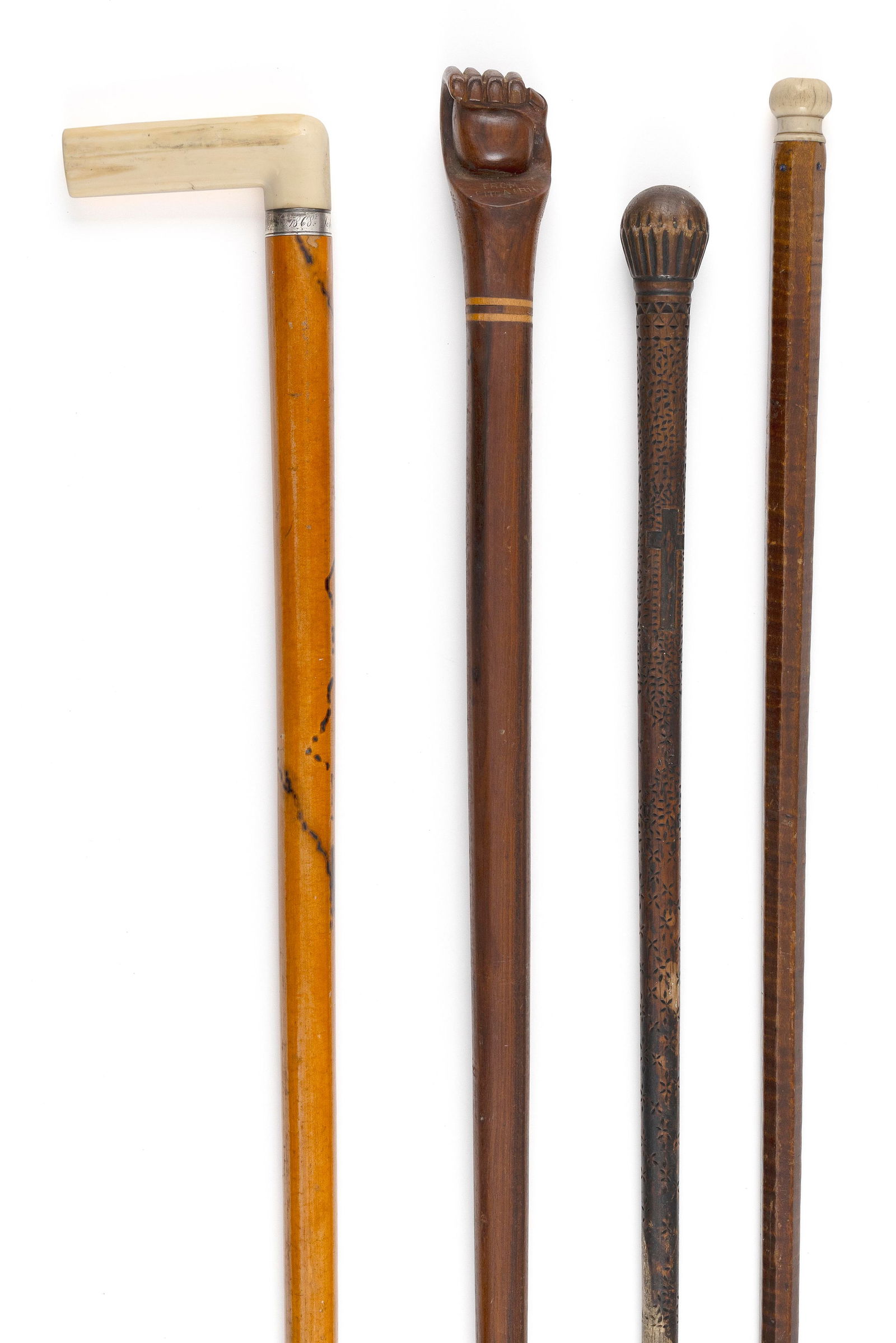 FOUR CANES 19th Century Lengths from 34" to 36.5".: FOUR CANES19th Century1) Wooden handle carved as a fist gripping a ball.2) Decoratively carved wooden handle and shaft, marked "From Picairn" (presumably Pitcairn Island).3) Bone knob handle. Tiger ma
