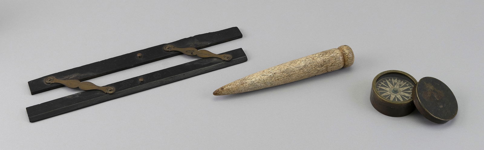 THREE MARITIME OBJECTS 19th Century: THREE MARITIME OBJECTS19th Century1) Pair of ebony parallels. Lengths 12".2) Whalebone fid with knop terminal. Length 8".3) Brass-cased dry card pocket compass.
