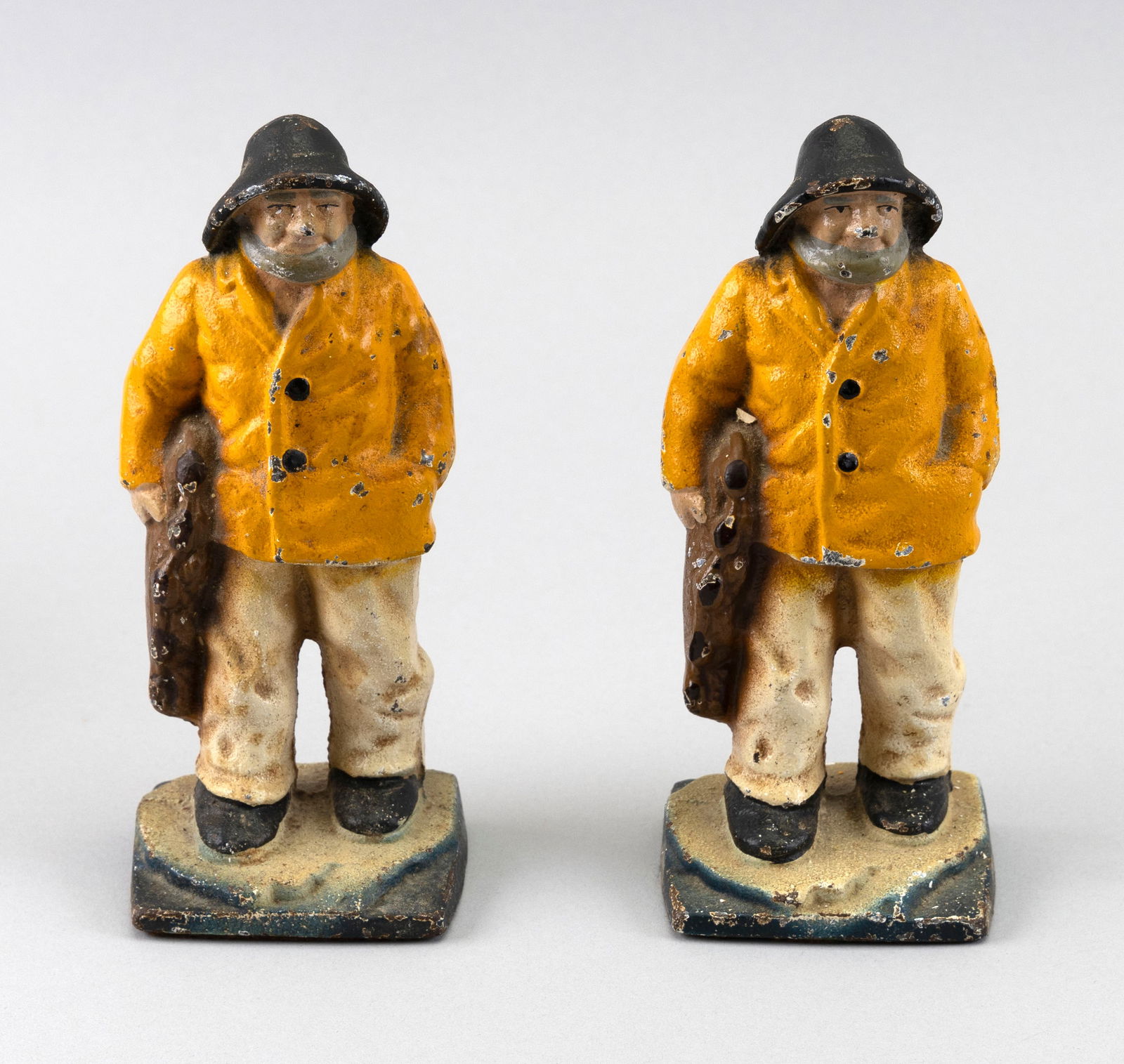 PAIR OF CAST IRON OLD SALT DOORSTOPS Early 20th Century Heights 7".: PAIR OF CAST IRON OLD SALT DOORSTOPSEarly 20th CenturyWearing black caps and yellow slickers and holding fishing nets.Heights 7".