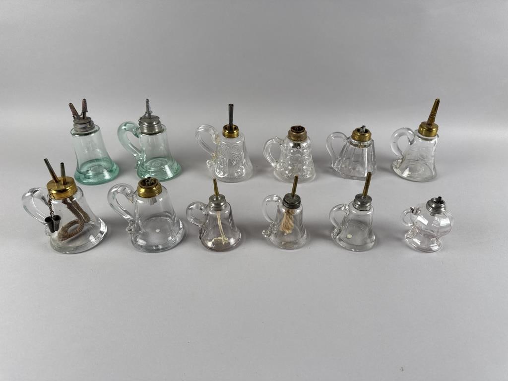 TWELVE CLEAR GLASS FINGER LAMPS 19th Century Heights from 3.75" to 6.5".: TWELVE CLEAR GLASS FINGER LAMPS19th CenturyAll with applied handles. All retain their original burners.Heights from 3.75" to 6.5".