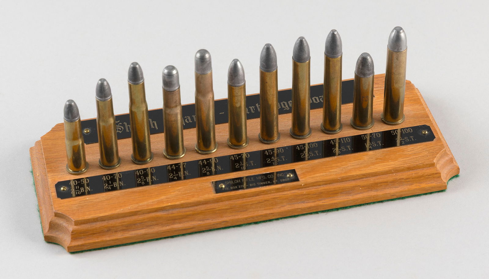 SHILOH SHARPS CARTRIDGE BOARD 20th Century Length 11".: SHILOH SHARPS CARTRIDGE BOARD20th CenturyDisplay of 11 shells on a wooden base.Length 11".
