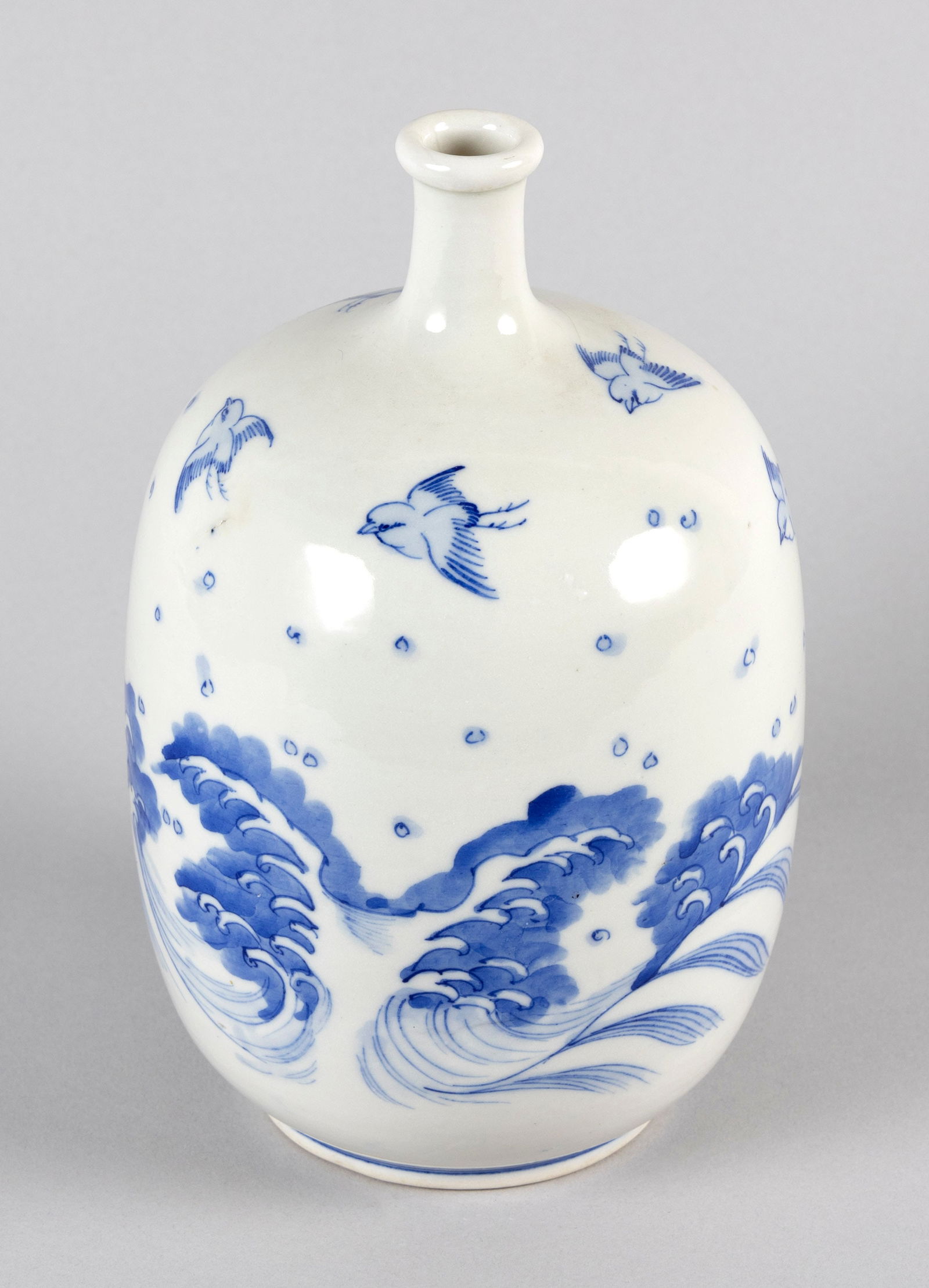 JAPANESE BLUE AND WHITE HIRADO PORCELAIN SAKE BOTTLE/VASE Late Meiji Period (Early 20th Century): JAPANESE BLUE AND WHITE HIRADO PORCELAIN SAKE BOTTLE/VASELate Meiji Period (Early 20th Century)Decoration of sparrows over waves.Height 9". Diameter 5".
