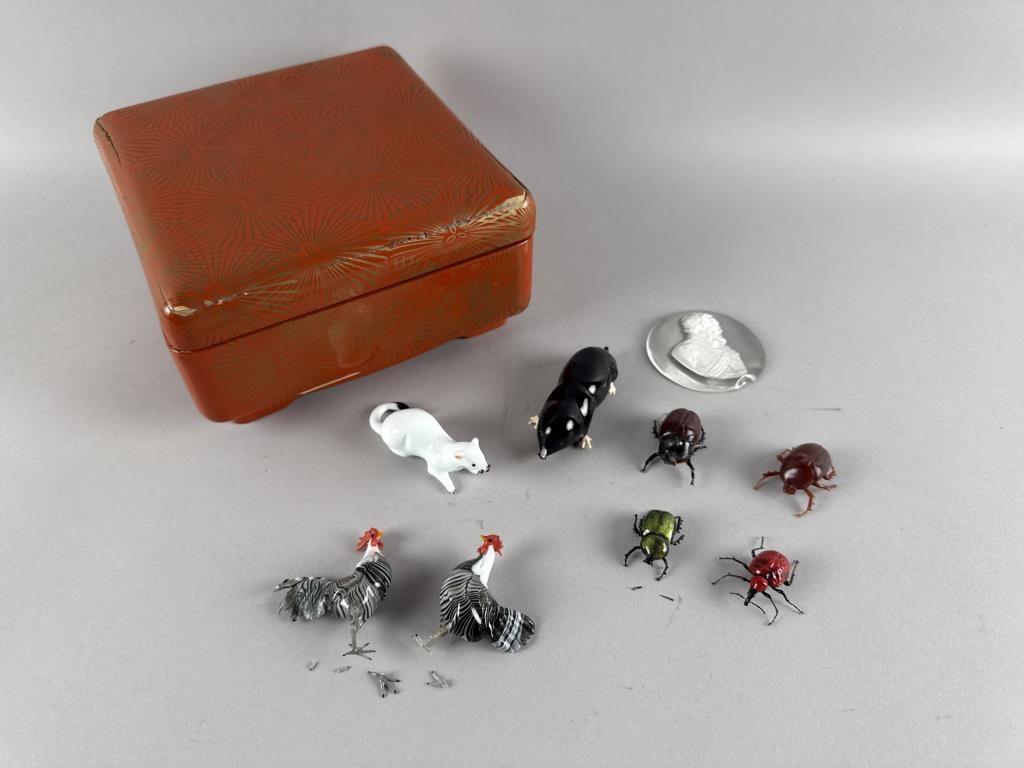 NINE GLASS ITEMS IN A LACQUER BOX Lacquer box height 4". Length 7.5". Width 7.75".: NINE GLASS ITEMS IN A LACQUER BOX20th Century red and gold lacquer box with artist's signature inside the lid. Glass items include:1-8) Eight Early 21st Century Venetian glass animals and insects, lik