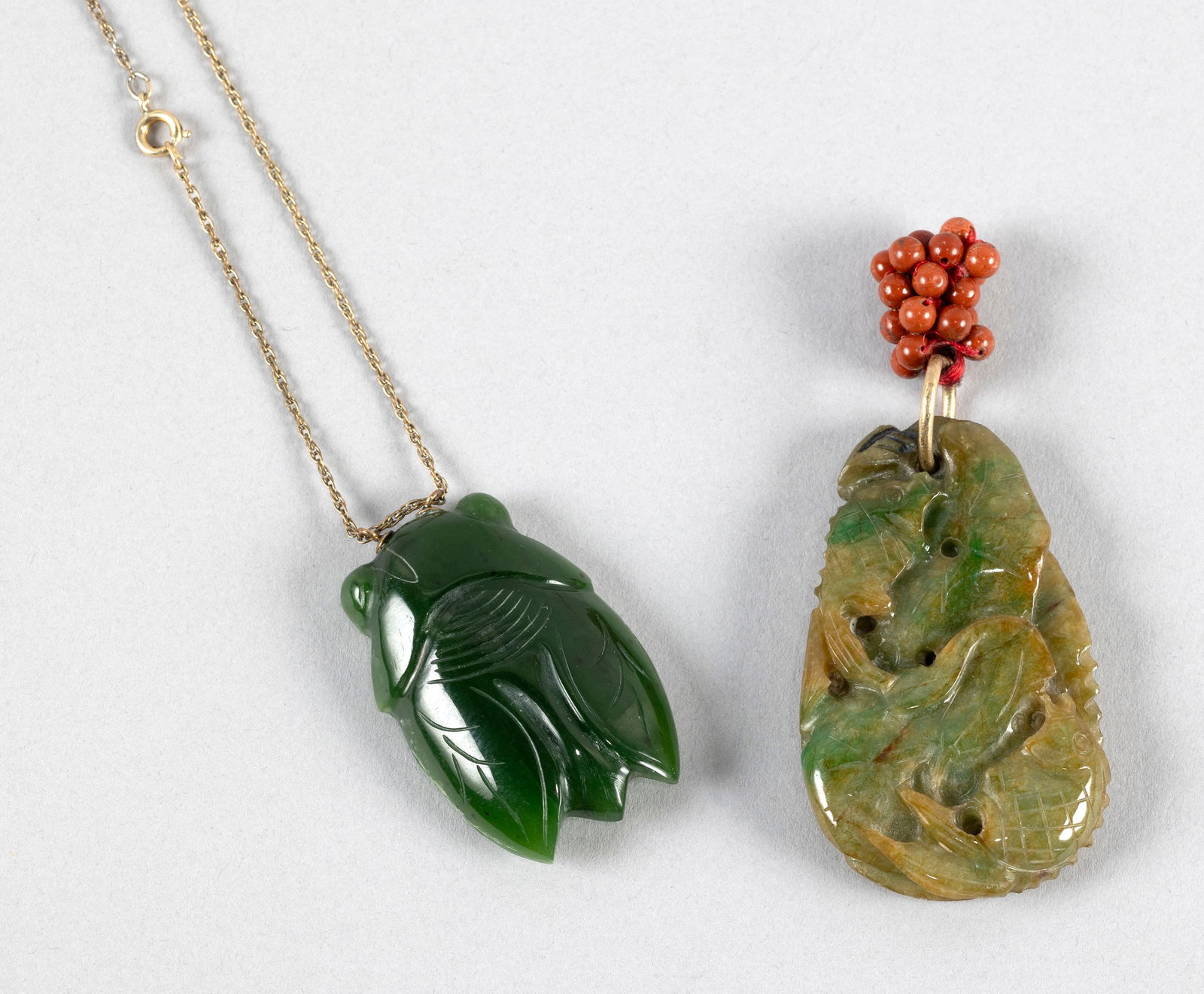 TWO CHINESE GREEN JADE PENDANTS 19th/20th Century: TWO CHINESE GREEN JADE PENDANTS19th/20th Century1) In the form of a cicada. Suspended from an unmarked gold link chain. Length 2".2) Flat pebble carved with a crane and lotus on one face and a carp an