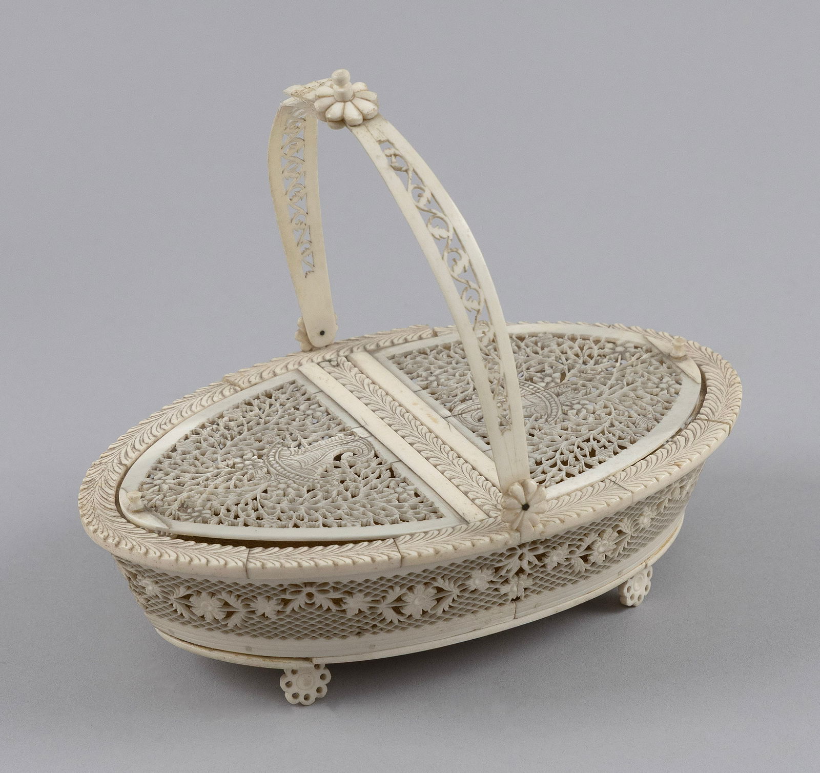 CHINESE EXPORT CARVED IVORY BASKET 19th Century Height to rim 1.75". Length 6.75".: CHINESE EXPORT CARVED IVORY BASKET19th CenturyDelicate carved and pierced designs throughout. Swing handle with a floriform knop and hinges, and a pierced scrolling acanthus leaf design. Top with palm