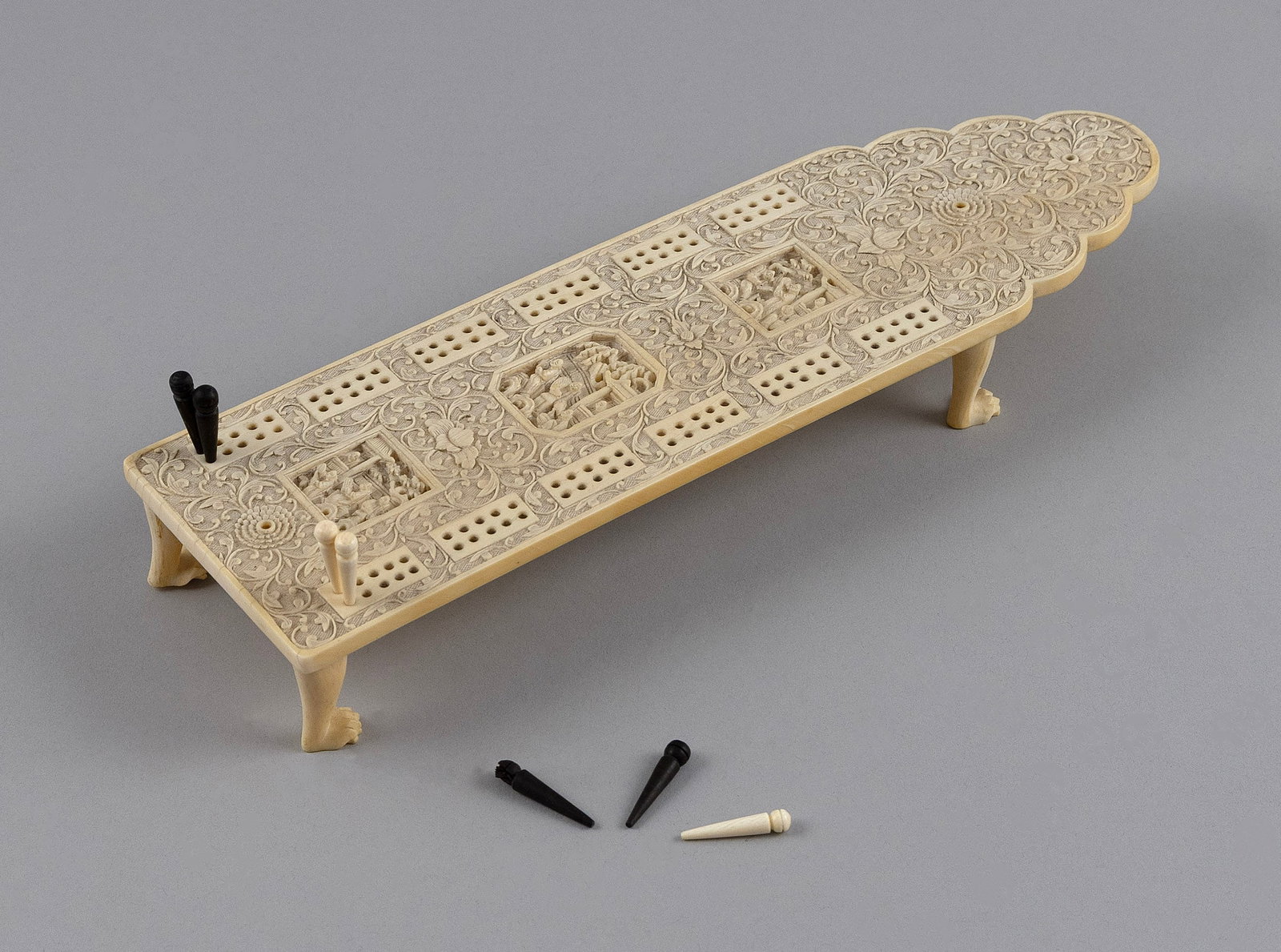 CHINESE EXPORT RELIEF-CARVED IVORY CRIBBAGE BOARD Second Half of the 19th Century Height 1.375".: CHINESE EXPORT RELIEF-CARVED IVORY CRIBBAGE BOARDSecond Half of the 19th CenturyScrolling foliage design with three finely executed landscape panels at the center of the game track. Paneled box on the