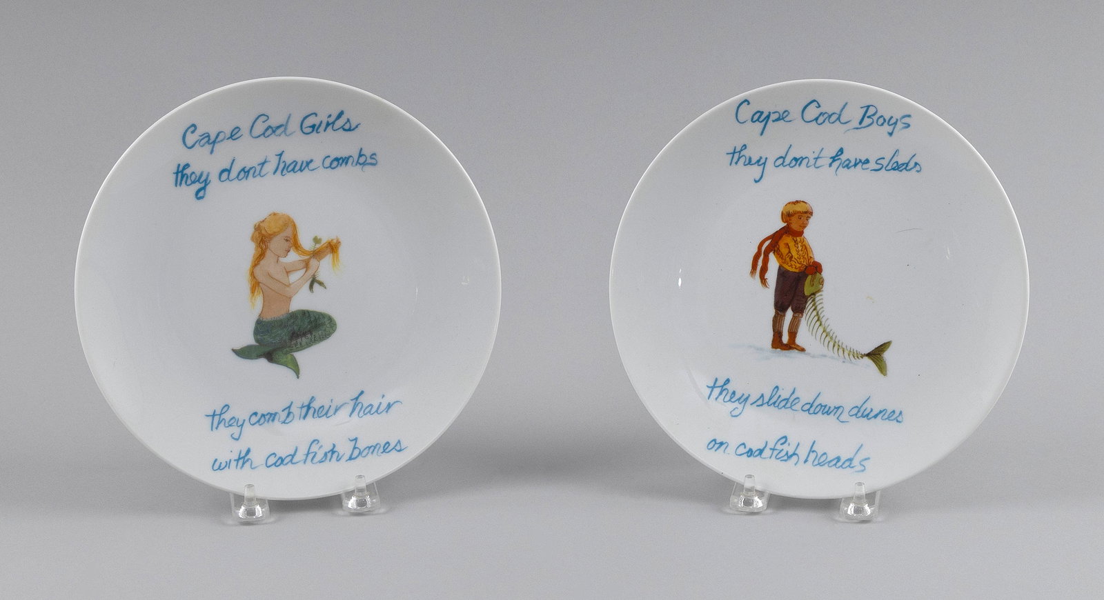 TWO PLATES WITH ELIZABETH MUMFORD-STYLE DECORATION Contemporary Diameters 8.75".: TWO PLATES WITH ELIZABETH MUMFORD-STYLE DECORATIONContemporaryPrinted "Cape Cod Girls they don't have combs They comb their hair with codfish bones" and "Cape Cod Boys they don't have sleds They slide