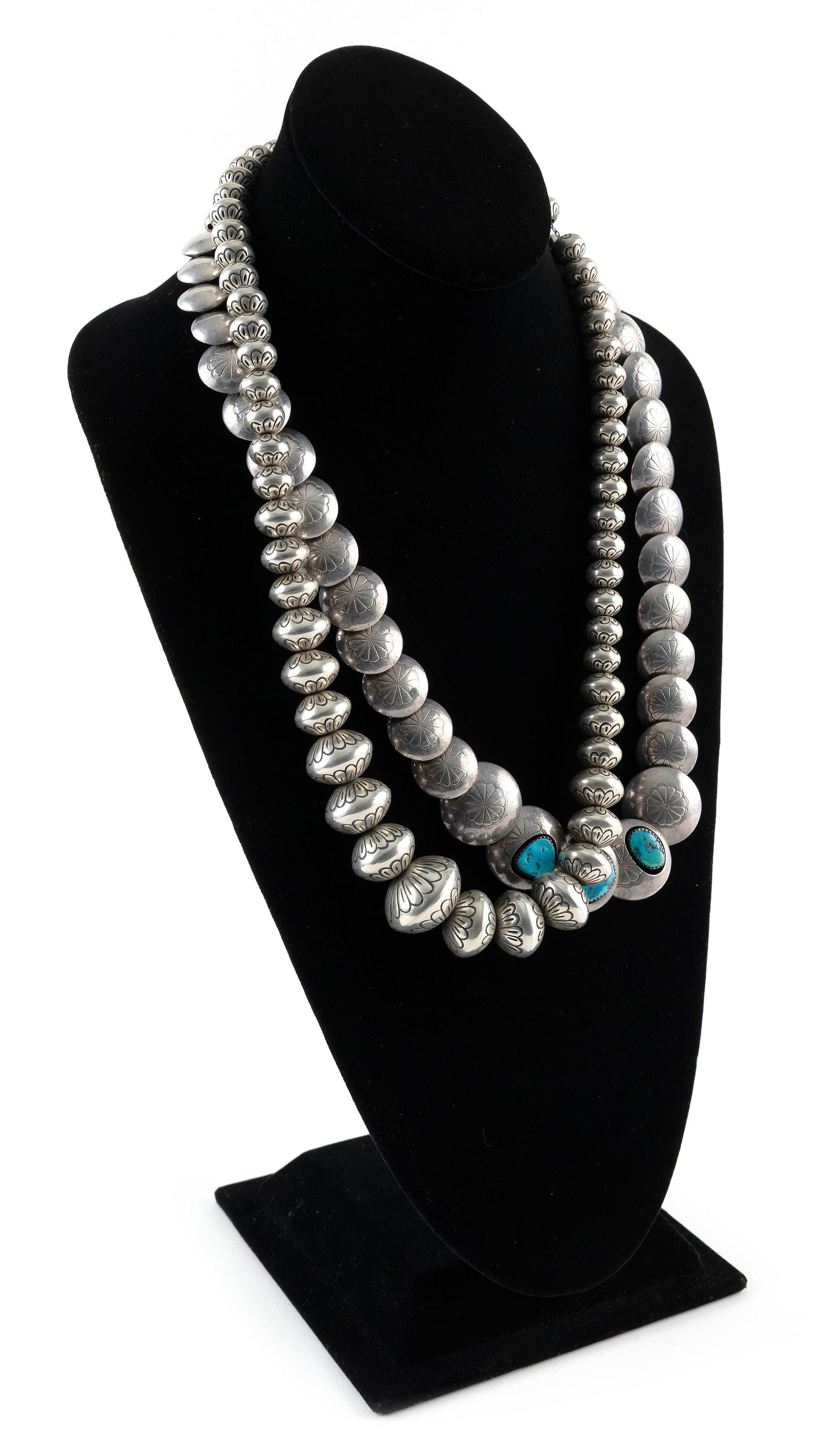 TWO NAVAJO SILVER BEAD NECKLACES Mid-20th Century: TWO NAVAJO SILVER BEAD NECKLACESMid-20th Century1) Silver graduated disc beads with stamped chrysanthemum design. Three largest with turquoise nuggets in sawtooth bezels. Silver chain with cone clasps