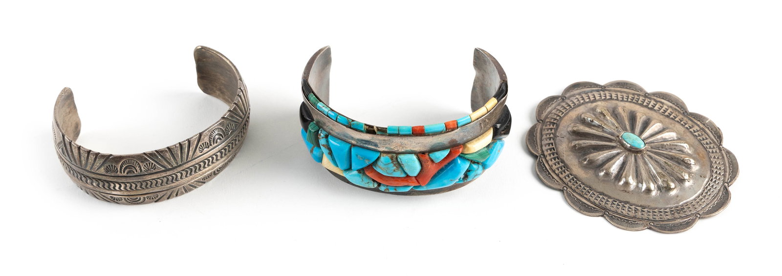 THREE PIECES OF NAVAJO SILVER AND TURQUOISE JEWELRY Mid-20th Century Approx. 192 grams: THREE PIECES OF NAVAJO SILVER AND TURQUOISE JEWELRYMid-20th Century1) Cuff bracelet with inset stones. Unmarked. Width 3".2) Cuff bracelet with stamped designs. Initialed "TP". Width 2.675".3) Oval bu