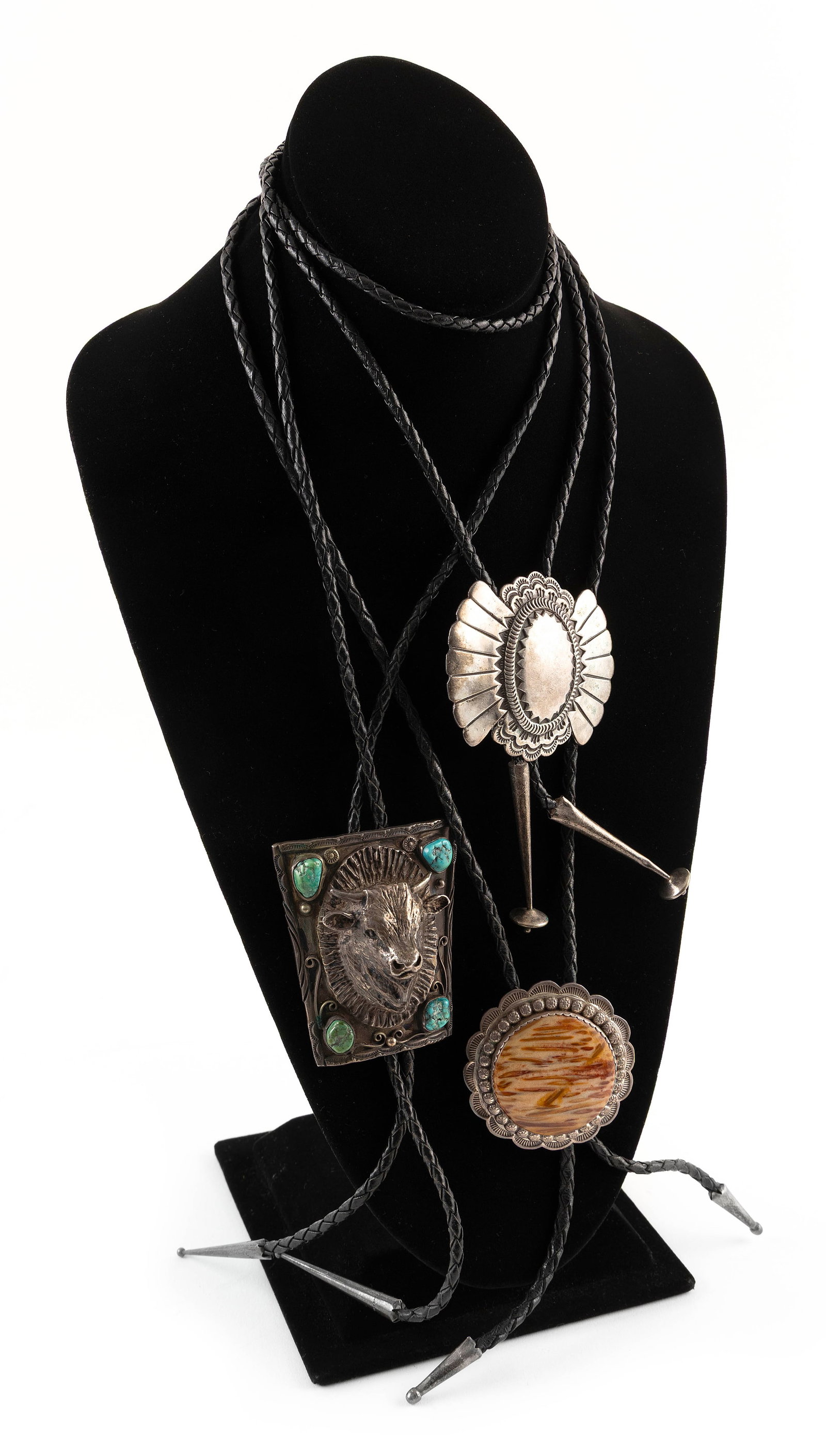 THREE NAVAJO SILVER AND LEATHER BOLO TIES Mid- to Late 20th Century: THREE NAVAJO SILVER AND LEATHER BOLO TIESMid- to Late 20th Century1) Steer's head clasp with applied flourishes and four turquoise nuggets. Silver unmarked. Clasp height 2.75". Width 2.25". Depth appr
