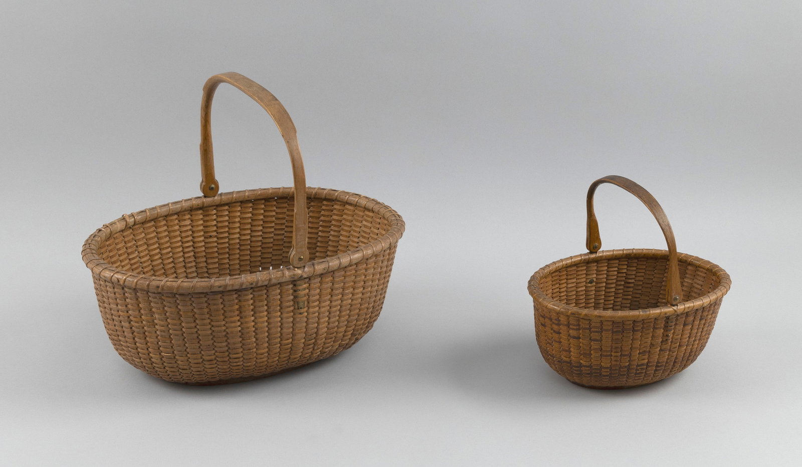 TWO OVAL NANTUCKET BASKETS Early 20th Century Heights 4" and 5". Lengths 8" and 12". (1 of 5)