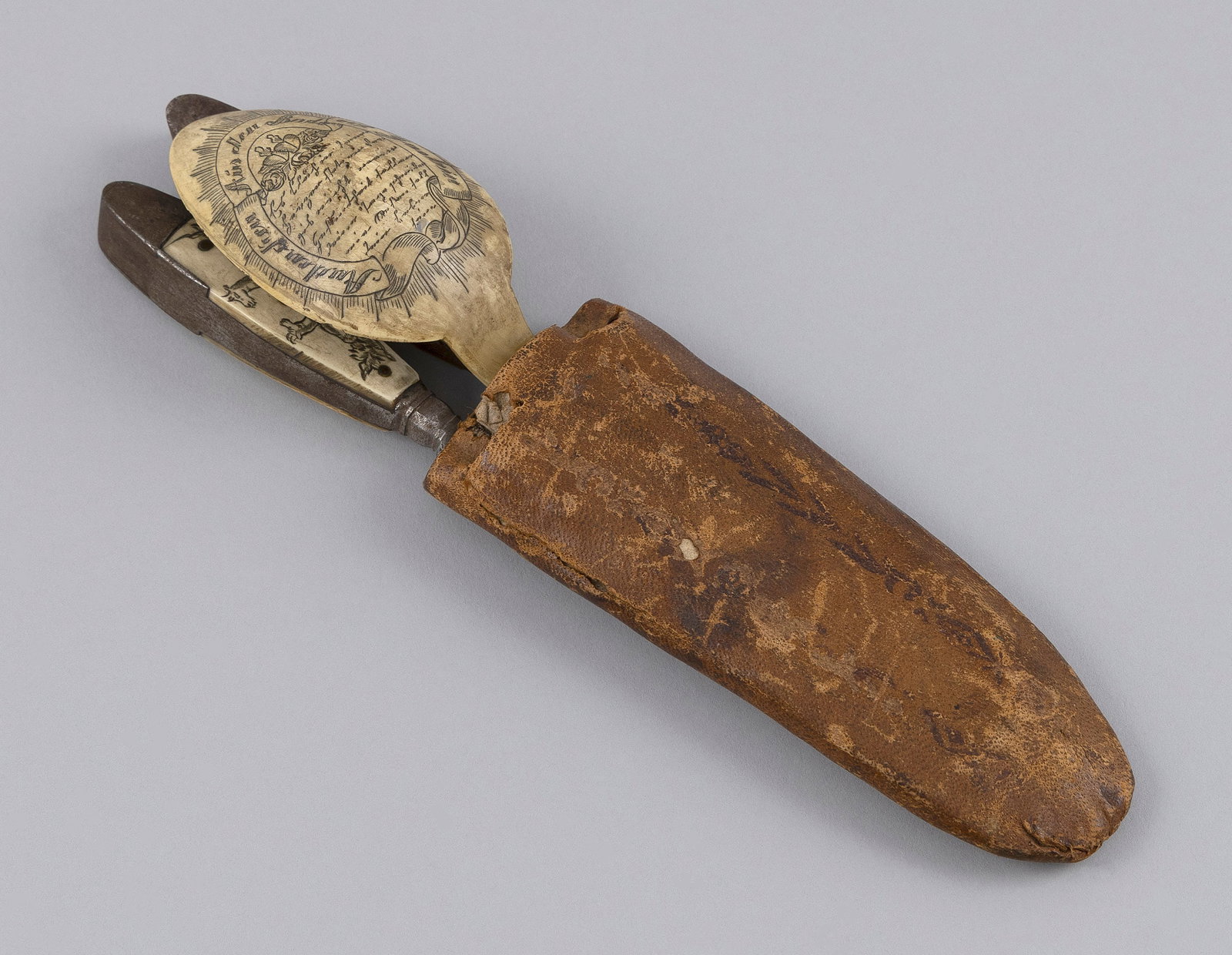 SET OF CONTINENTAL STAG ANTLER-HANDLED UTENSILS 19th Century Length in sheath 8.75".: SET OF CONTINENTAL STAG ANTLER-HANDLED UTENSILS 19th Century Spoon engraved on both sides with passages. Handles engraved with mythical animals and Tyrolean figures. In a fitted leather sheath. Length