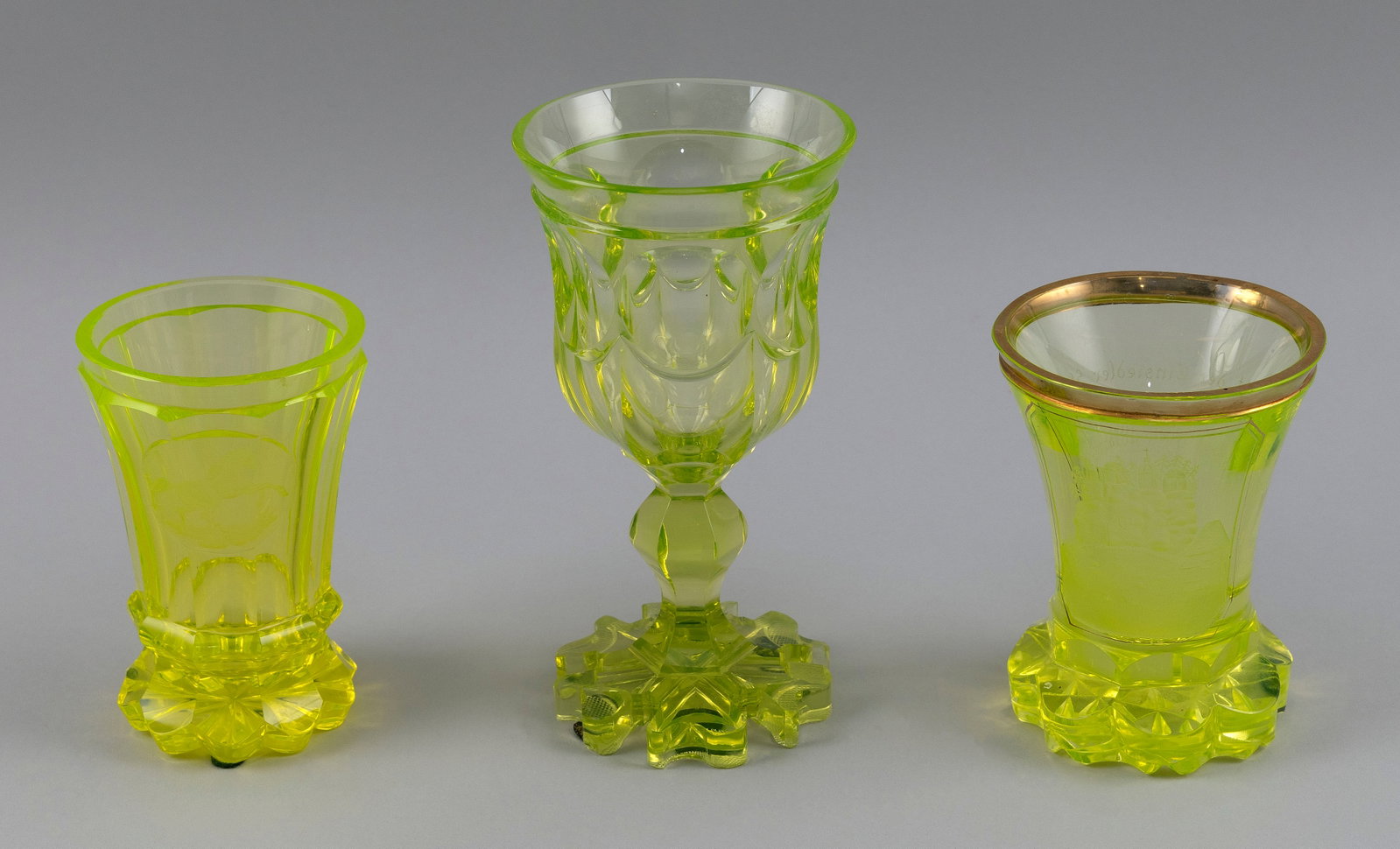 THREE PIECES OF BIEDERMEIER BOHEMIAN URANIUM GLASS Mid-19th Century: THREE PIECES OF BIEDERMEIER BOHEMIAN URANIUM GLASS Mid-19th Century 1) Stemmed goblet. Height 7.25". 2) Footed glass with engraved design of a rearing horse. Height 5". 3) Footed beaker with engraved 