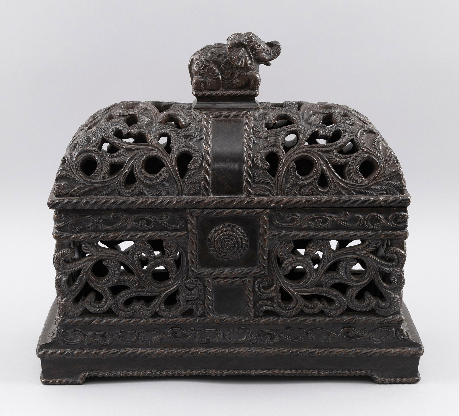 ANGLO-INDIAN OPEN-CARVED COVERED BOX Height 16". Length 17". Width 6".: ANGLO-INDIAN OPEN-CARVED COVERED BOX Made of faux rosewood. Decoration of scrolling vines and leaves. Cover with an elephant-form knop. Height 16". Length 17". Width 6".