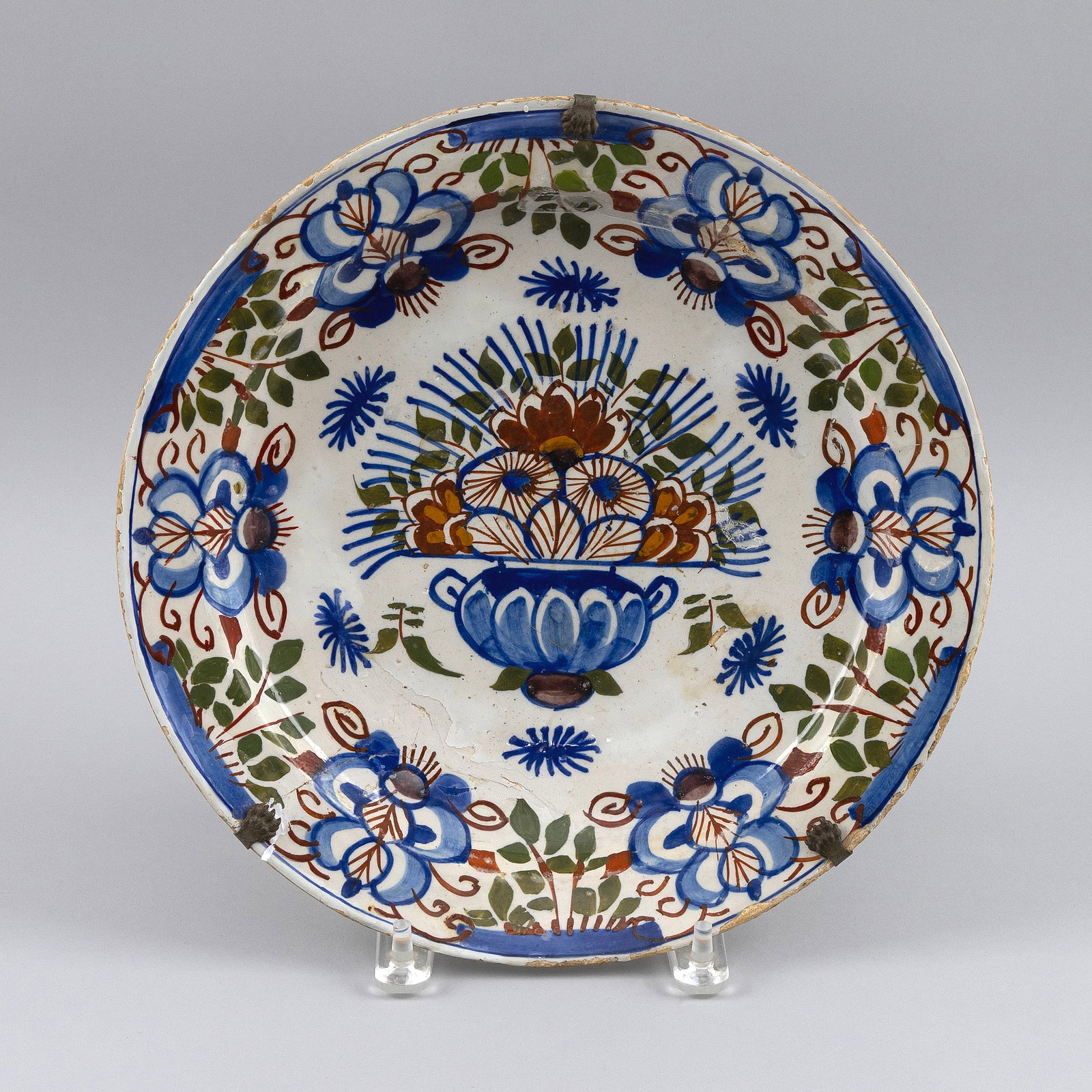 DELFT POLYCHROME CHARGER The Netherlands, 19th Century Diameter 12".: DELFT POLYCHROME CHARGER The Netherlands, 19th Century Rust, green and blue decoration of a floral vase at center and flowers and foliage around the border. Diameter 12".