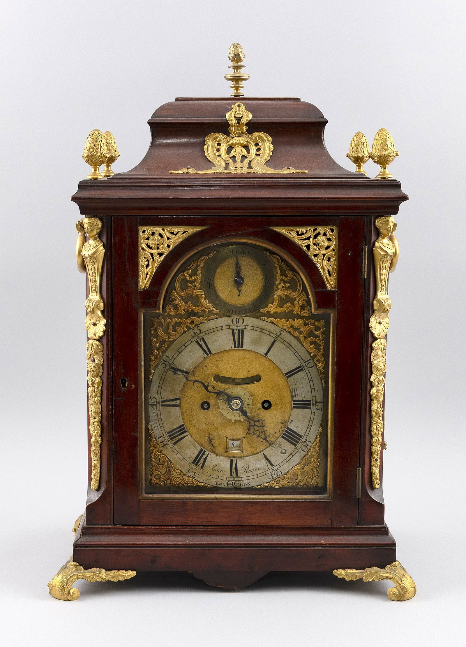 GEORGIAN BRACKET CLOCK BY ISAAC ROGERS London, Late 18th Century Height 21". Width 14". Depth 9.5".: GEORGIAN BRACKET CLOCK BY ISAAC ROGERS London, Late 18th Century Mahogany case with brass pineapple finials, figural quarter-columns and feet. Silvered dial with brass spandrels. Time, date and strike