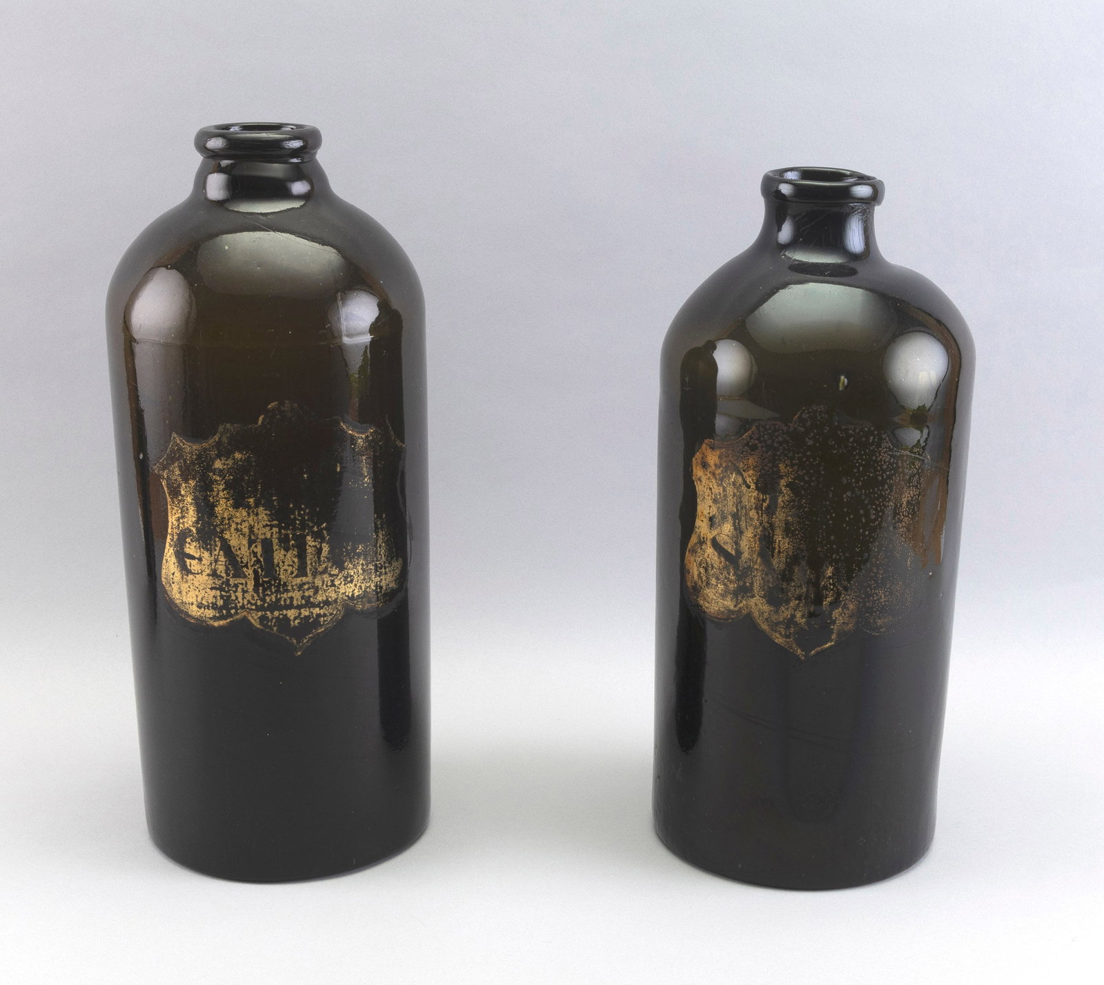 PAIR OF MOSS GREEN GLASS APOTHECARY BOTTLES 19th Century Heights 13.5".: PAIR OF MOSS GREEN GLASS APOTHECARY BOTTLES 19th Century Show traces of gilt shield-shaped labels. Heights 13.5".