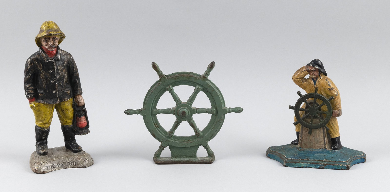 THREE CAST IRON NAUTICAL DOORSTOPS Early 20th Century Heights from 6.5" to 9".: THREE CAST IRON NAUTICAL DOORSTOPS Early 20th Century Two "Old Salts" and a ship's wheel. Heights from 6.5" to 9".