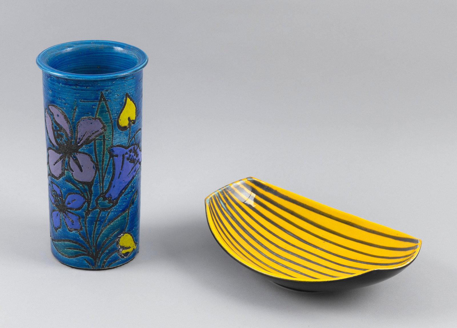 TWO PIECES OF BITOSSI RIMINI POTTERY Italy, 20th Century: TWO PIECES OF BITOSSI RIMINI POTTERY Italy, 20th Century 1) Aldo Londi cylinder vase with decoration of purple and yellow flowers against on a blue ground. Stamped on base. Height 9.25". 2) Melon-form