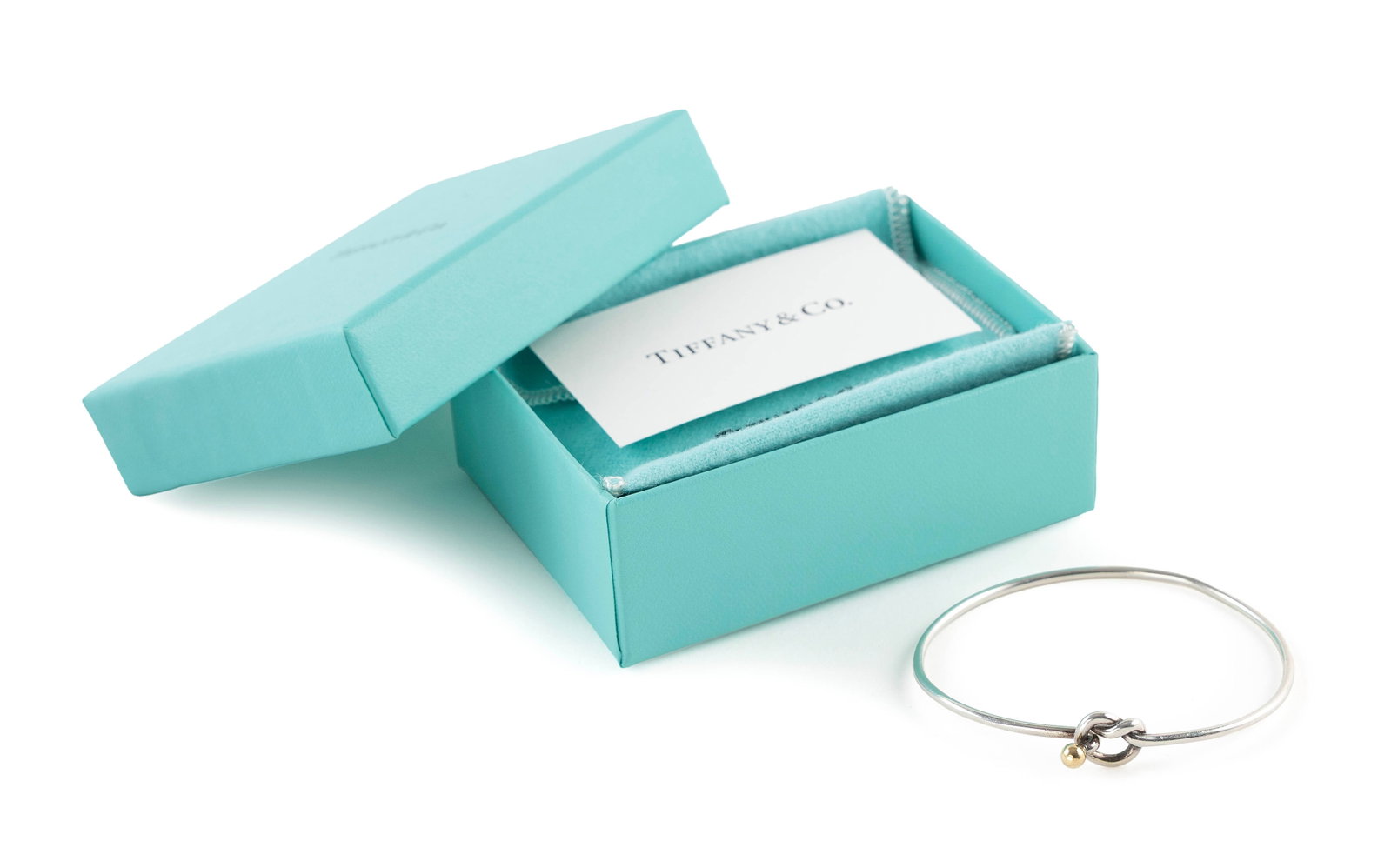 TIFFANY & CO. STERLING SILVER AND 18KT YELLOW GOLD BANGLE BRACELET Approx. 4.3 total dwt.: TIFFANY & CO. STERLING SILVER AND 18KT YELLOW GOLD BANGLE BRACELET Knot/ball clasp with an approx. 4.0mm round gold ball. Stamped. Wire width approx. 2.0mm. Length 7". Approx. 4.3 total dwt.