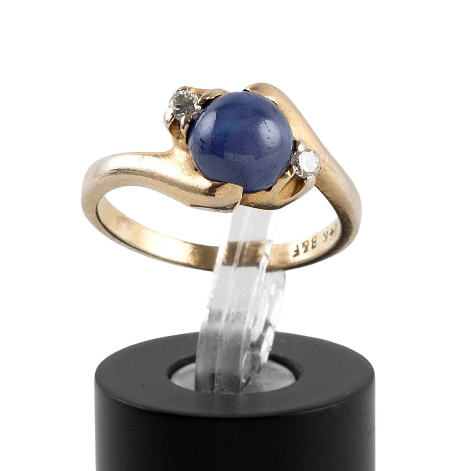 14KT YELLOW GOLD, DIAMOND AND STAR SAPPHIRE RING Approx. 2.0 total dwt.: 14KT YELLOW GOLD, DIAMOND AND STAR SAPPHIRE RING Bypass design with one approx. 7.0mm round cabochon blue star sapphire and two small round-cut diamonds. Stamped. Size 6. Approx. 2.0 total dwt.